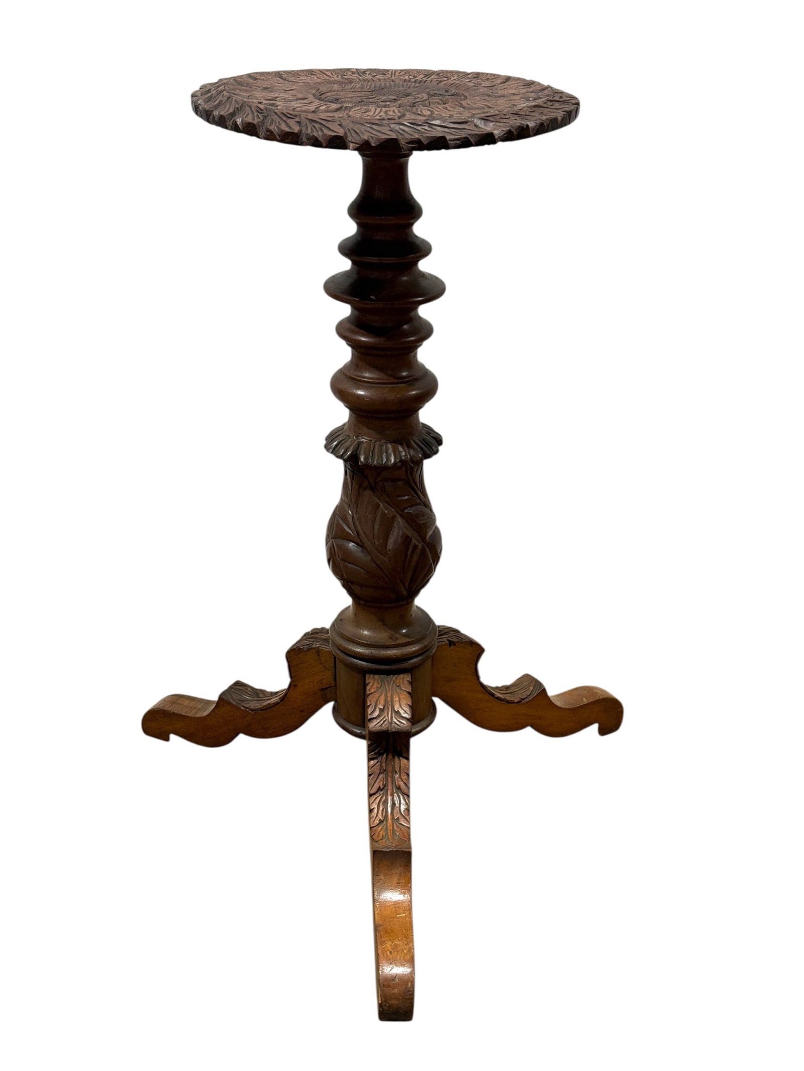 Anglo Indian Carved Wood Pedestal Table: A striking Anglo-Indian carved wood pedestal or plant stand, featuring a circular top deeply carved with radiating foliate decoration surrounding a central peacock medallion and finished with a serrat