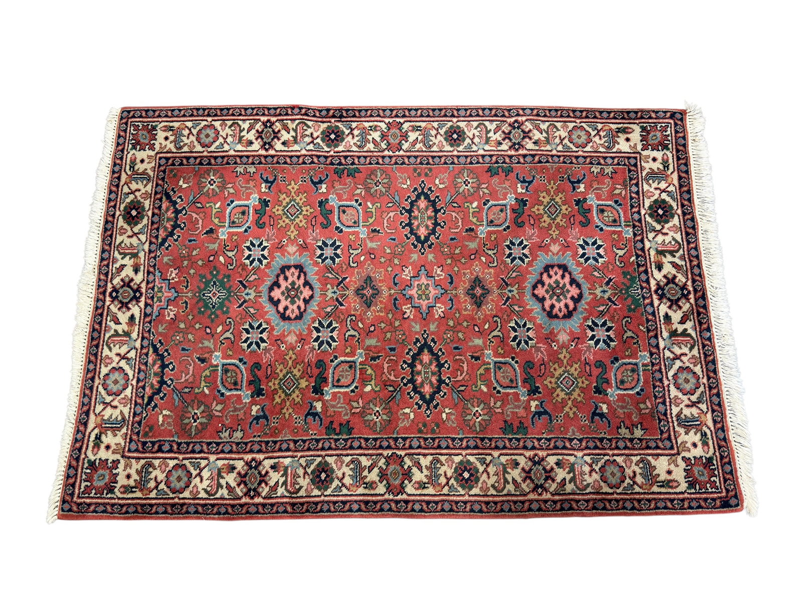 20th C. Persian Heriz Style Wool Area Rug: Hand-knotted wool area rug featuring a traditional Heriz-inspired allover geometric and floral design arranged across a warm coral-red field, centered by two bold blue, pink, and black medallions and 