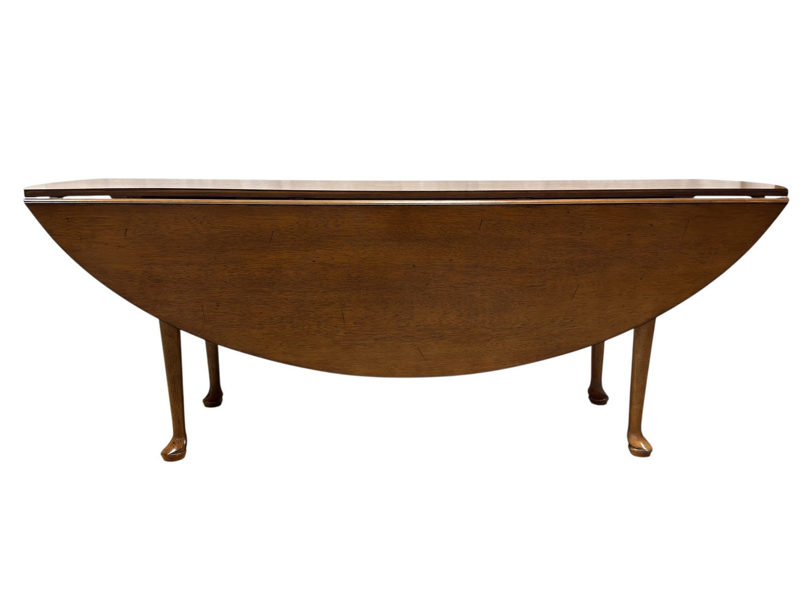 20th C. Queen Anne Style Mahogany Drop Leaf Dining Table: A handsome Queen Anne-style mahogany dining table featuring a long rectangular center section flanked by broad hinged drop leaves that create a graceful oval top when fully extended. The warm mahogany
