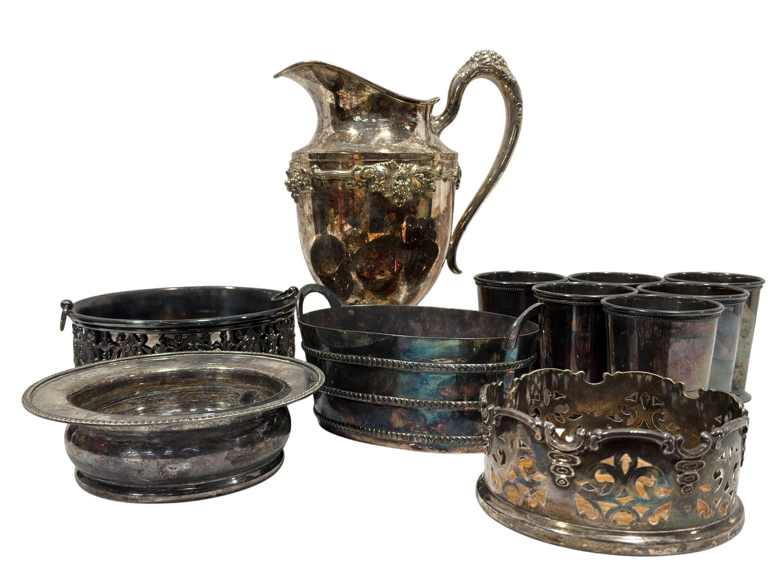 Assembled Victorian & Vintage Silverplate Hollowware Serving Collection: An extensive assembled collection of antique and vintage silverplate hollowware comprising a large ornate footed water pitcher or ewer with sweeping handle, flared spout, and richly applied grape, flo