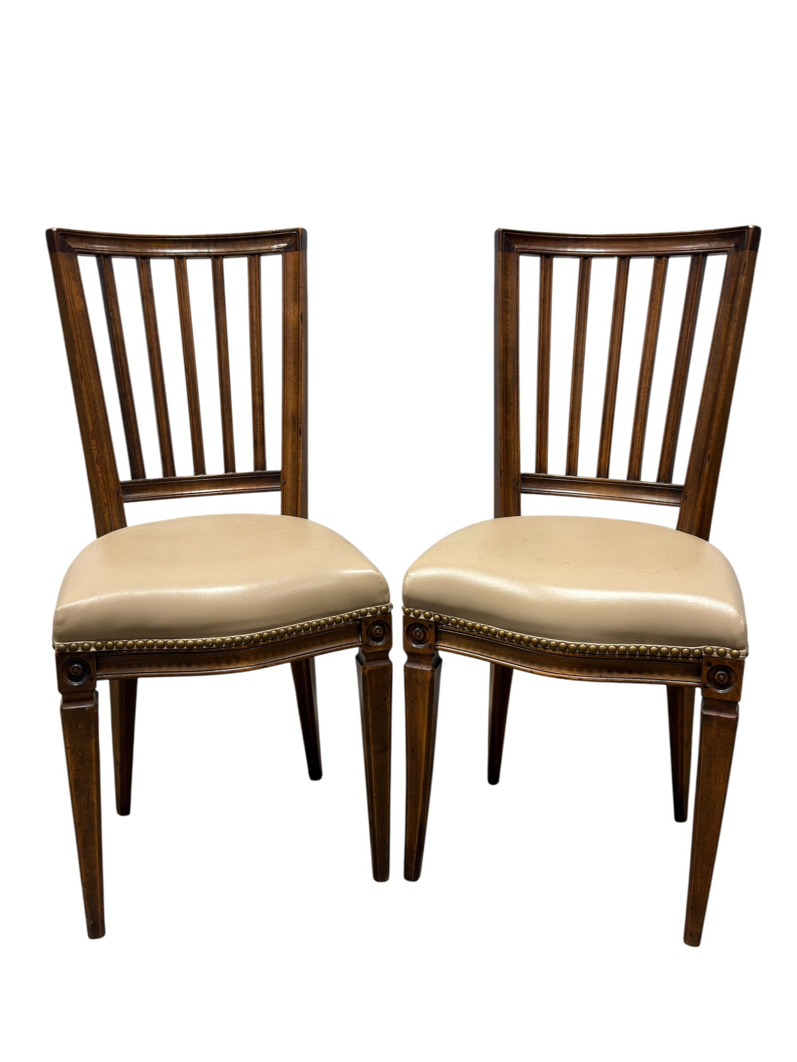 Pair of Louis XVI Style Walnut Side Chairs: A handsome pair of Louis XVI style side or dining chairs crafted in richly toned walnut, each featuring a gently bowed crest rail above a tall open back fitted with five slender vertical splats and a 
