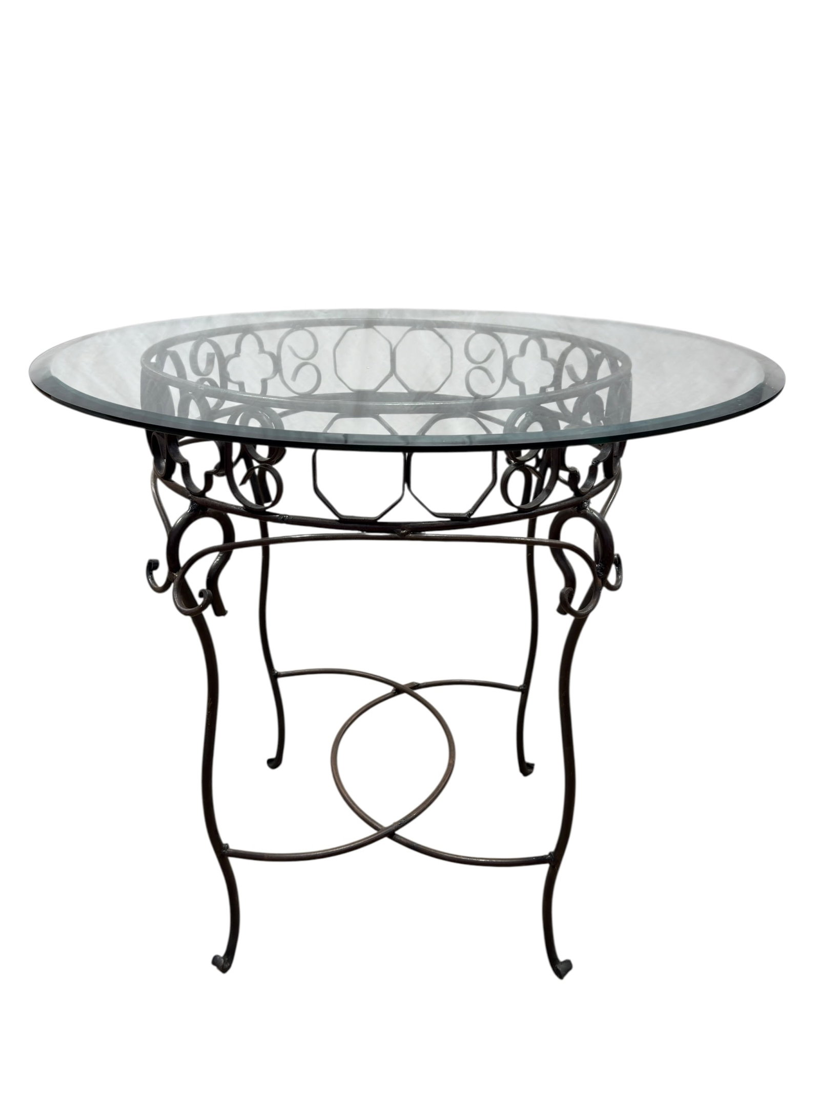 Vintage Mediterranean Revival Wrought Iron & Beveled Glass Round Dining Table: Decorative vintage round dining or center table featuring a substantial clear beveled glass top supported by an ornate dark wrought-iron base. The openwork apron is composed of repeating circular and 