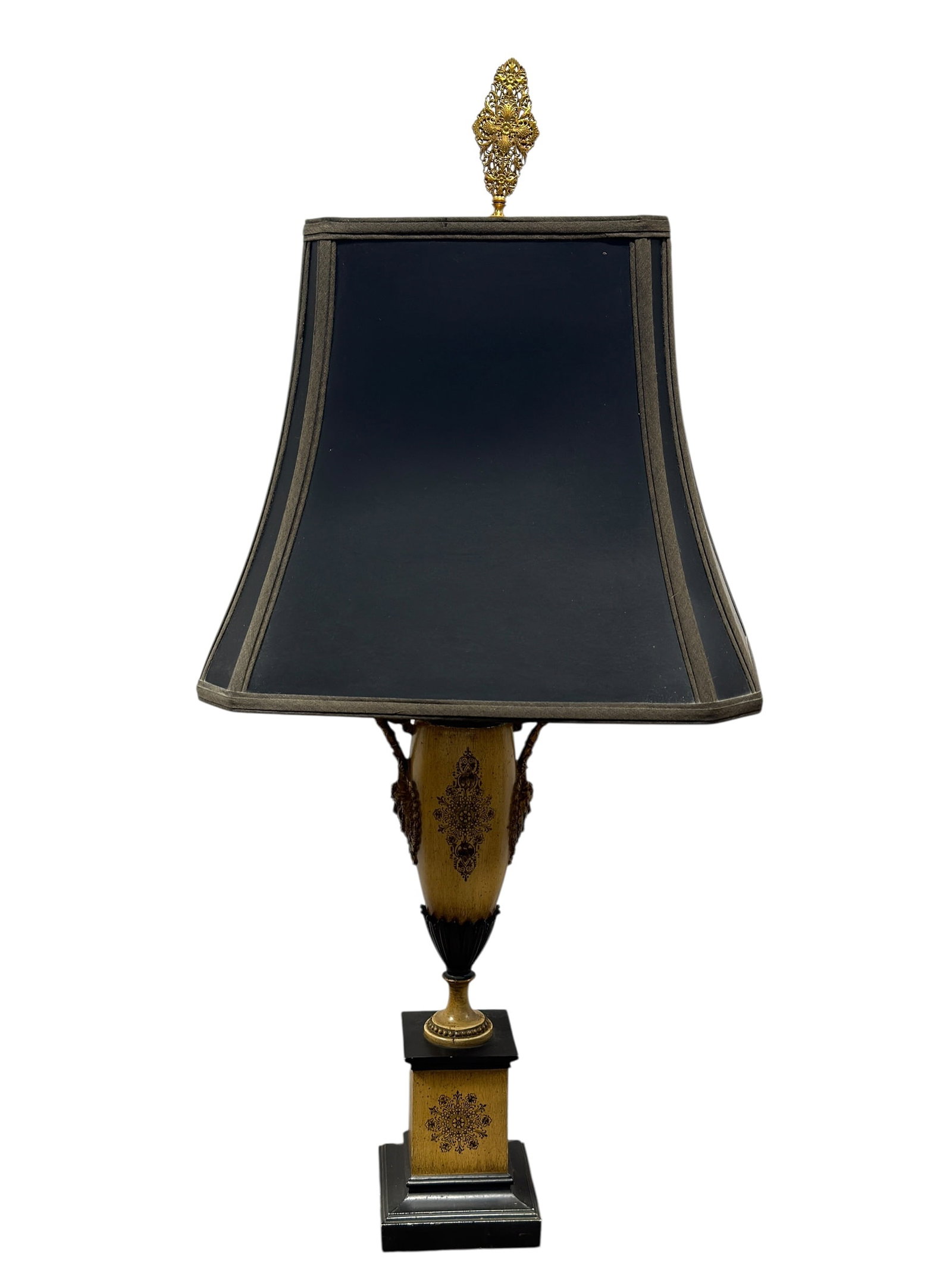 Vintage Neoclassical Urn-Form Table Lamp w/ Ornate Filigree Finial: Vintage neoclassical-style table lamp featuring an elongated urn-form body finished in warm antiqued gold with black floral and foliate transfer decoration, flanked by elaborate scrolling handles with