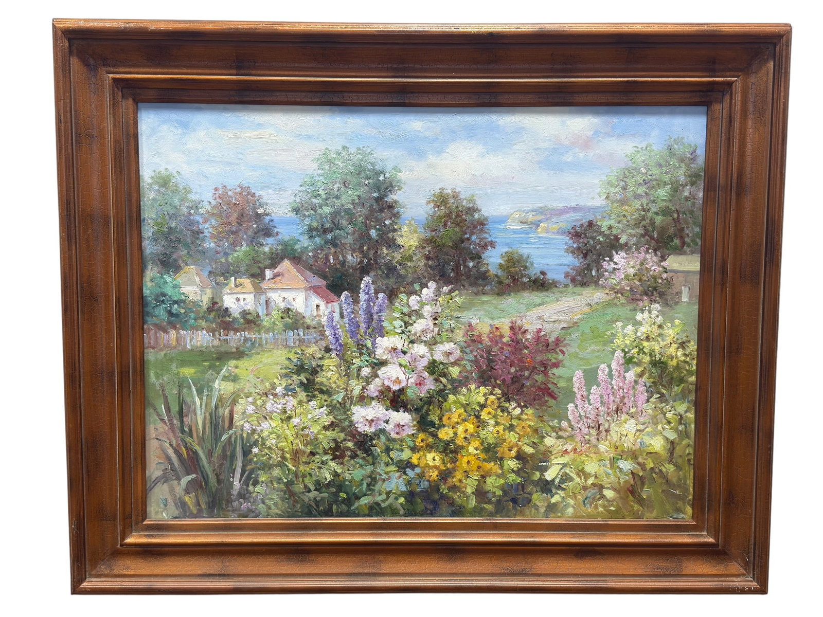 Large Oil on Canvas Coastal Garden Landscape: Large oil on canvas landscape depicting a lush flowering garden overlooking a broad expanse of blue water and a distant rocky shoreline. The composition is anchored by dense foreground plantings of wh