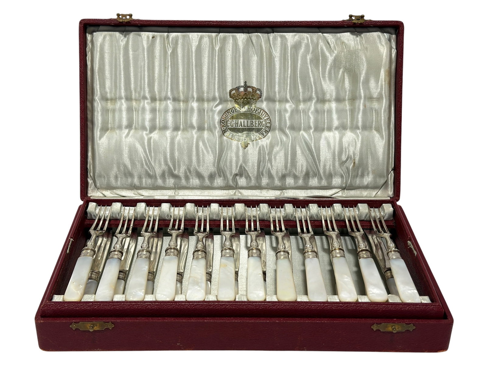 C.G. Hallberg Swedish Mother of Pearl Dessert Flatware Set in Case: An elegant early 20th-century Swedish dessert flatware service by C.G. Hallberg, presented in its original fitted burgundy case and combining luminous mother-of-pearl handles with bright metal mounts 