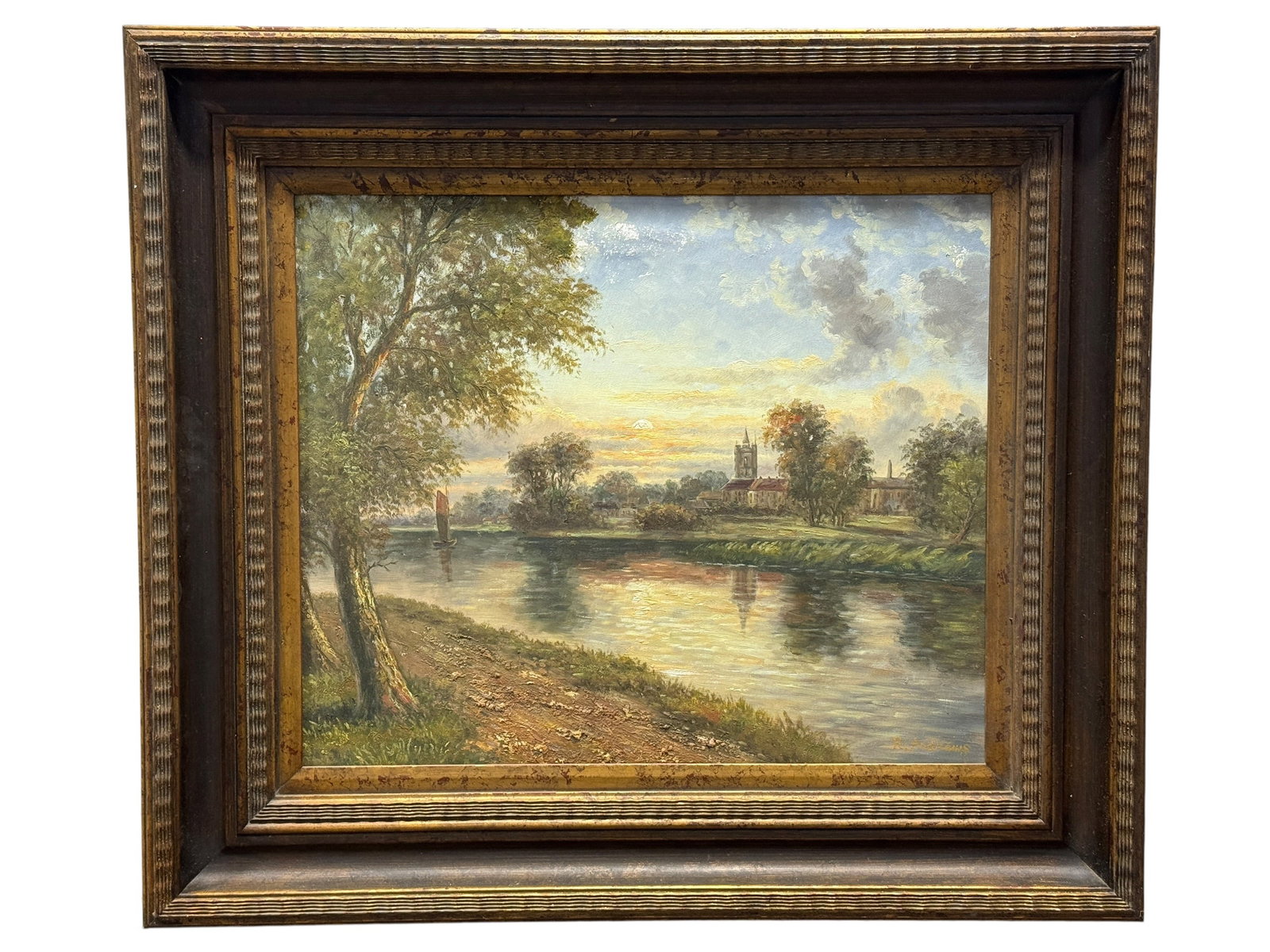 Signed R. Andrews River Landscape Oil on Canvas Painting: luminous pastoral river landscape captures the warmth of a setting sun as it reflects across calm water, drawing the eye toward a picturesque village dominated by a tall church tower in the distance. 