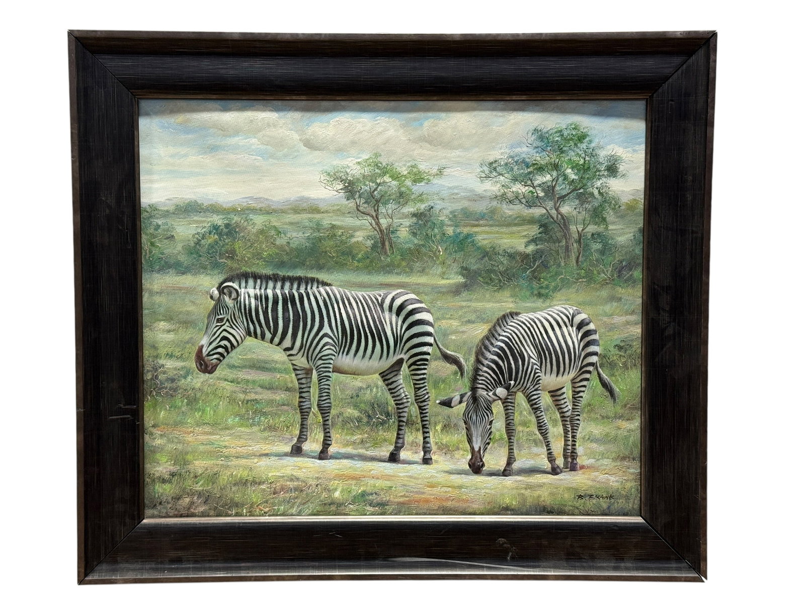 Signed R. Frank Zebra Landscape Oil on Canvas Painting: A striking wildlife scene depicting two zebras standing and grazing across an open African landscape, set against softly rendered trees, distant hills, and a broad atmospheric sky. Painted in oil on c