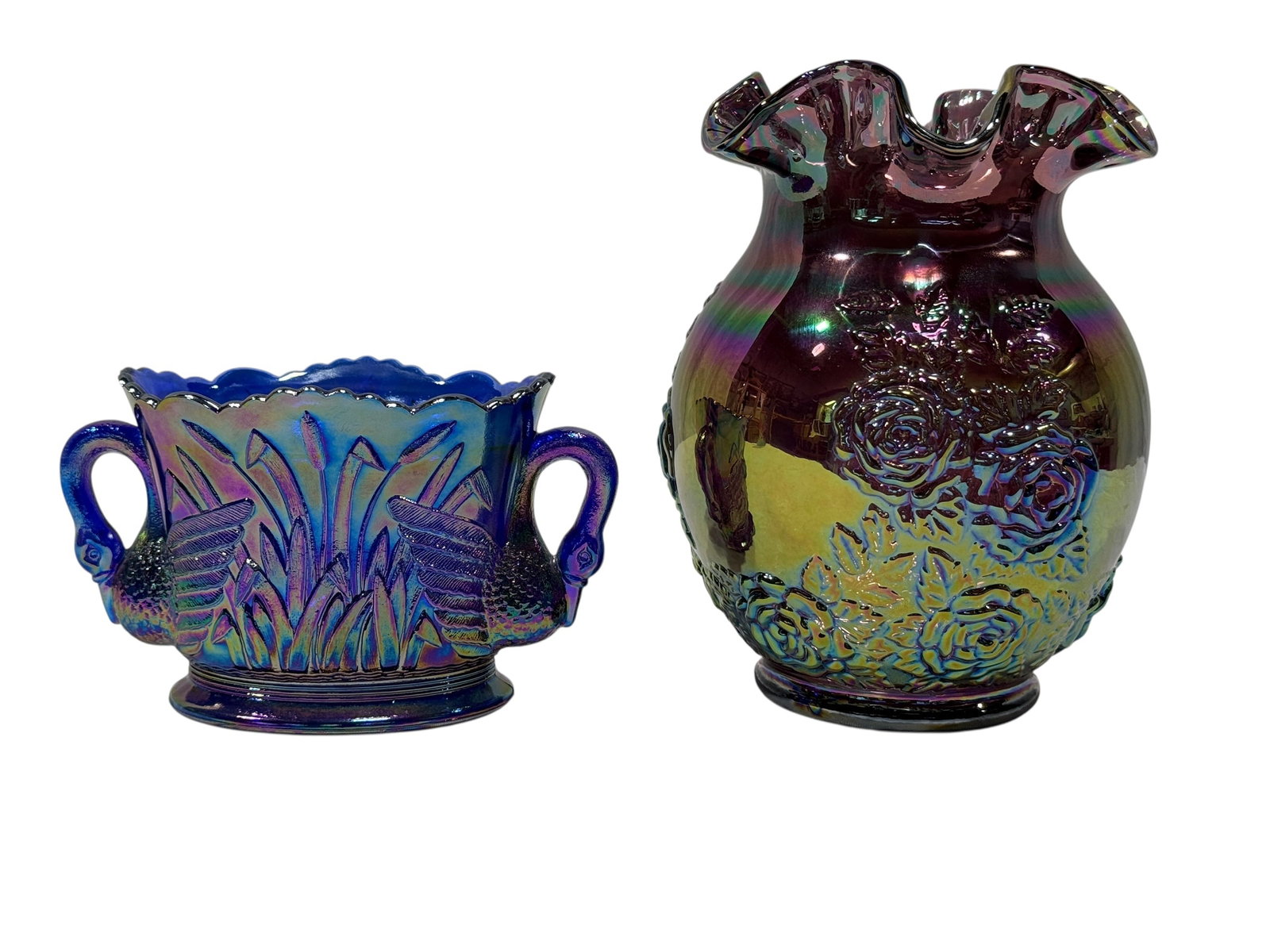 Fenton Purple Iridescent Carnival Glass Rose Vase & Westmoreland Swan Dish: A colorful two-piece grouping of purple iridescent carnival glass featuring a Fenton vase with a rounded body, raised rose and foliage decoration, and dramatically ruffled rim, finished with strong vi