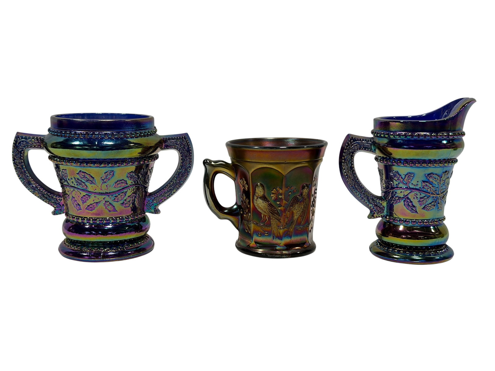 (3) Vintage Iridescent Carnival Glass Creamer, Sugar Bowl & Bird Mug: A colorful three-piece grouping of vintage iridescent carnival glass highlighted by a matching creamer and open sugar bowl in deep cobalt blue glass with strong purple, green, gold, and aqua iridescen