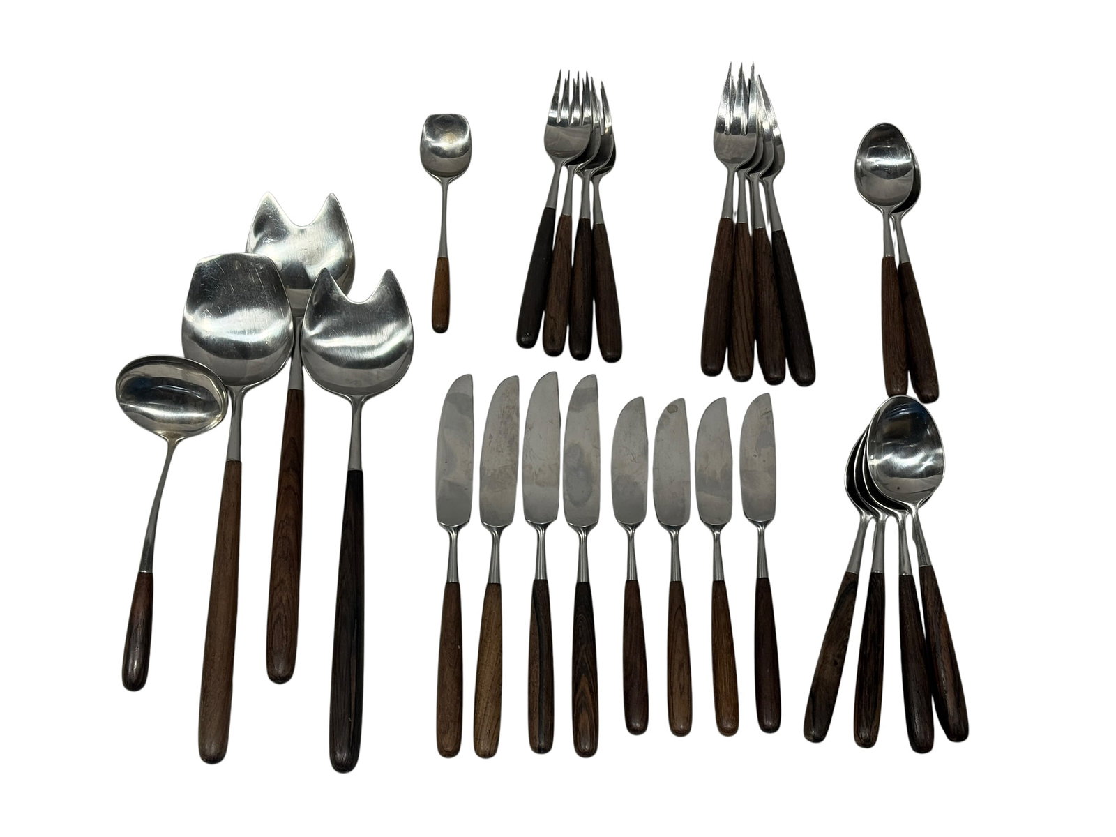 (27) Lauffer Norway MCM Teak Handled Stainless Steel Flatware Set: Stylish 27-piece Mid-Century Modern flatware and serving set by Lauffer, Norway, combining sleek Scandinavian stainless steel forms with warm teak wood handles. The design features long, gently tapere