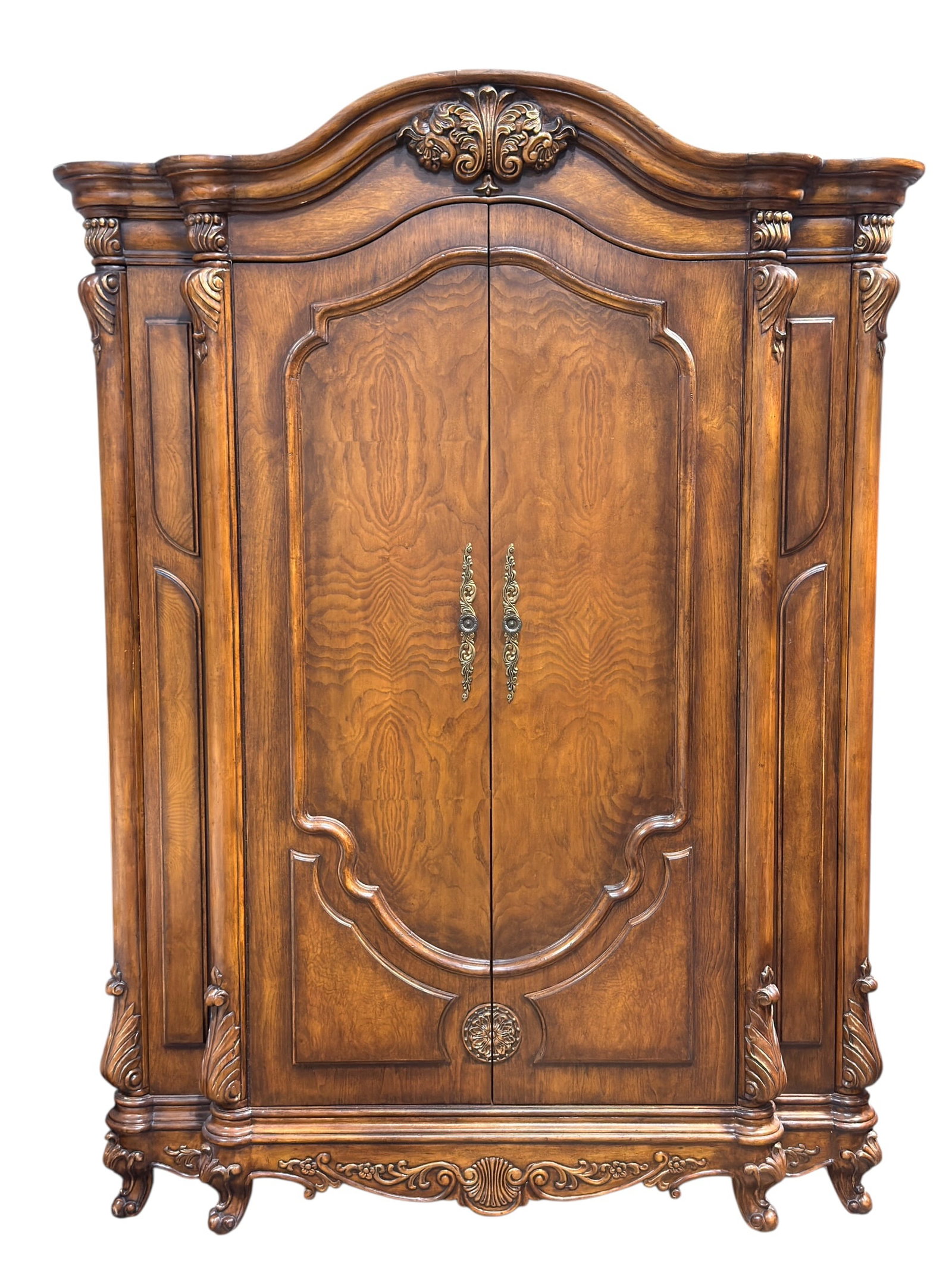 French Provincial Style Entertainment Armoire Cabinet: Large French Provincial style entertainment armoire cabinet featuring an elaborately molded bonnet crest with carved foliate decoration, paneled double doors, decorative brass-tone hardware, and a war
