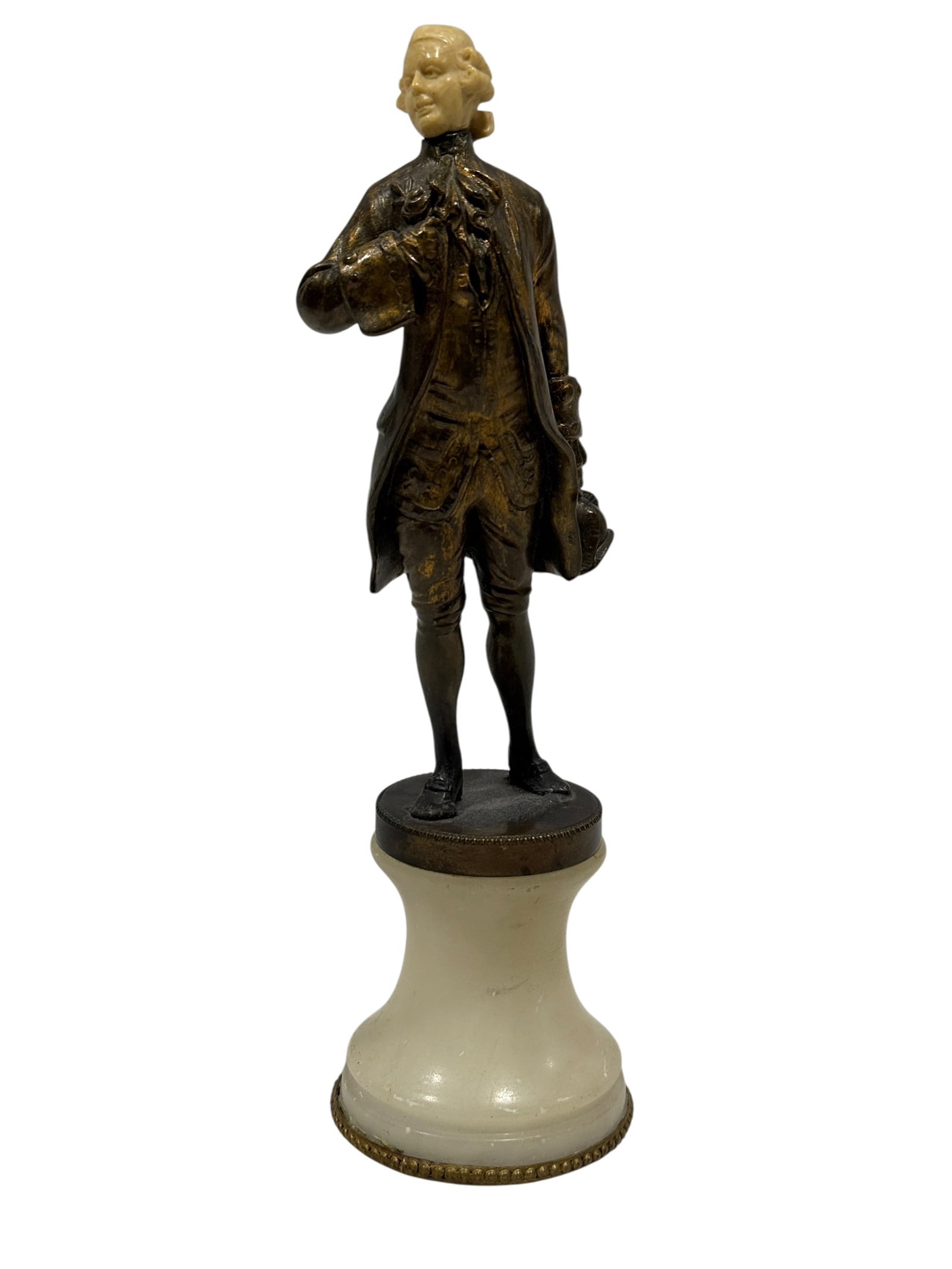 Early 20th Century Bronze and Carved Bone Gentleman Figure on Alabaster Base: Charming early 20th century Continental figural sculpture depicting an elegantly dressed 18th-century gentleman standing in a formal pose, modeled in a dark patinated bronze with finely detailed frock