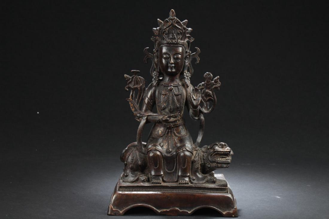 Chinese Bronze Deity Statue: Riding a mythical beast, the hands held in the lap, wearing long flowing robe, adorned with jewelry and a headdress, the face with a serene expression. Height: 11.25 in