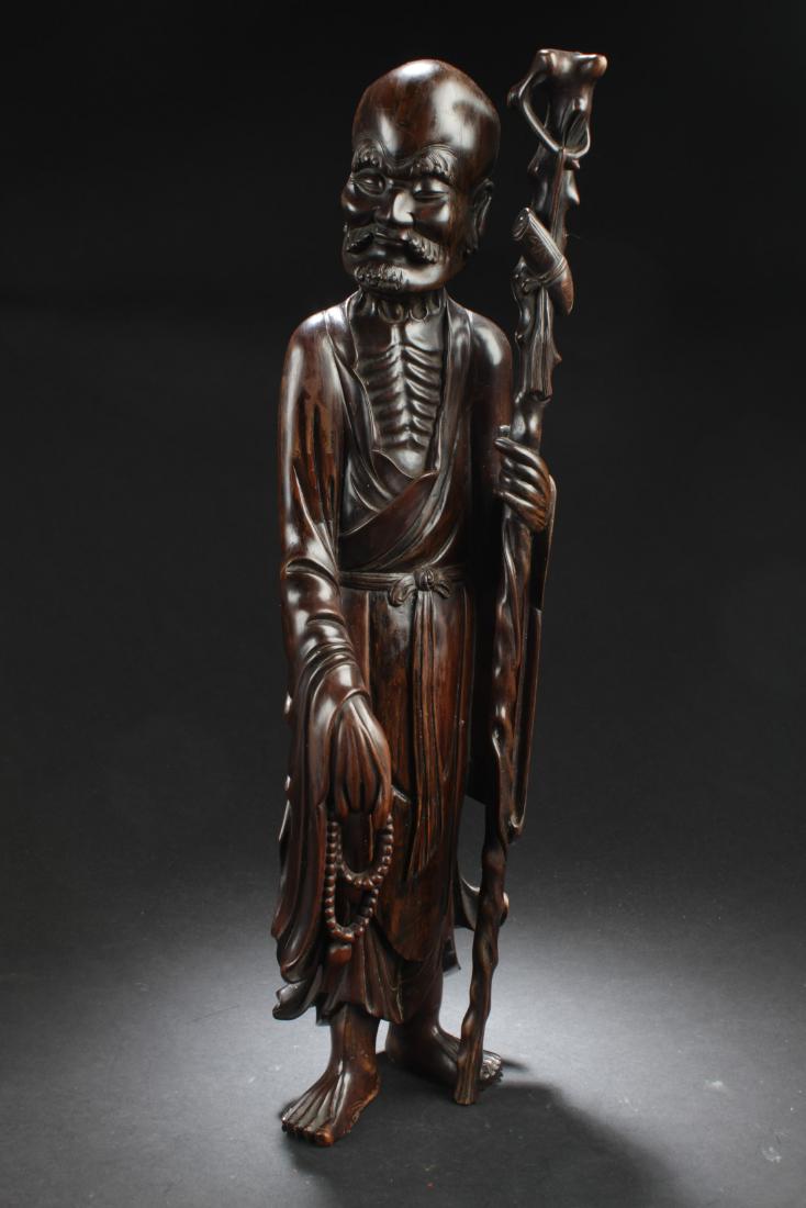 Antique Chinese Bowood Carved Statue: Antique Chinese Bowood Carved Statue, depicting a luohan wearing flowing robes, left hand holding a walking stick and right hand holding prayer beads.Height: 19.5"