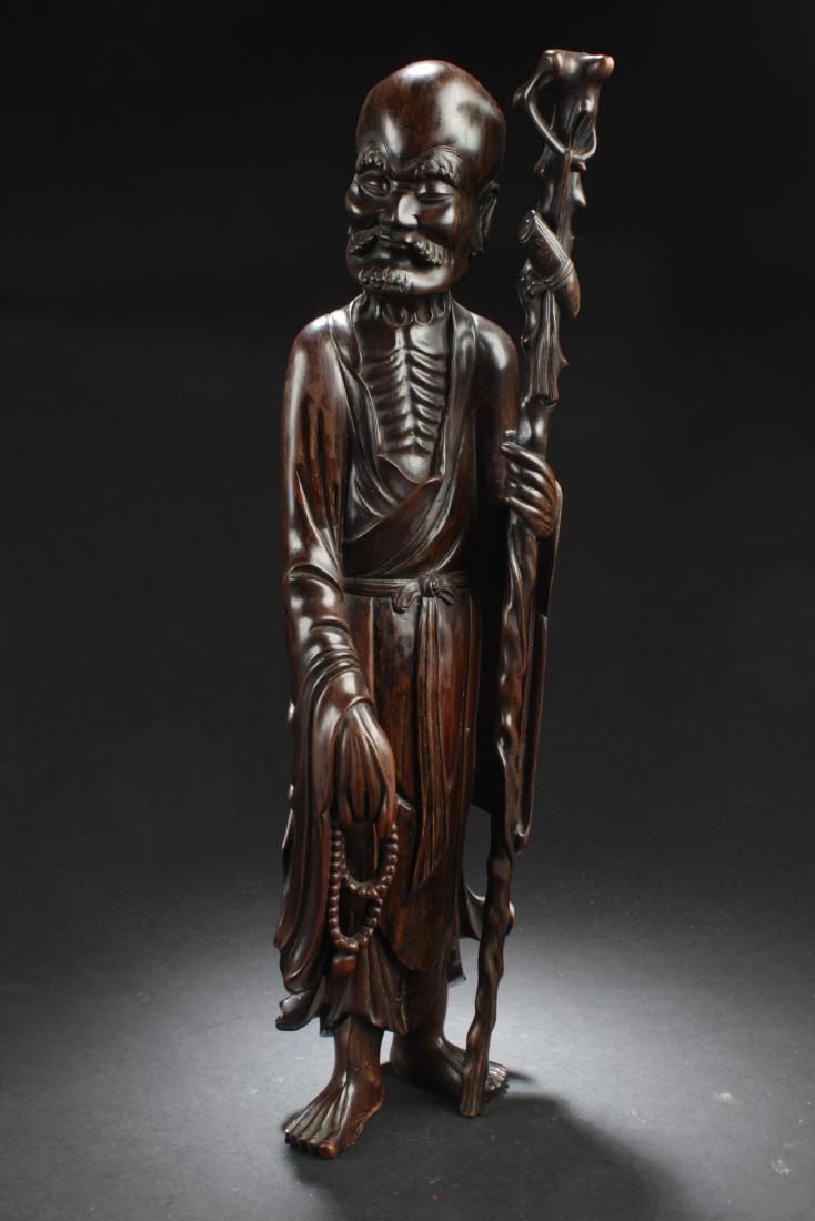 Antique Chinese Bowood Carved Statue: Antique Chinese Bowood Carved Statue, depicting a luohan wearing flowing robes, left hand holding a walking stick and right hand holding prayer beads.Height: 19.5"