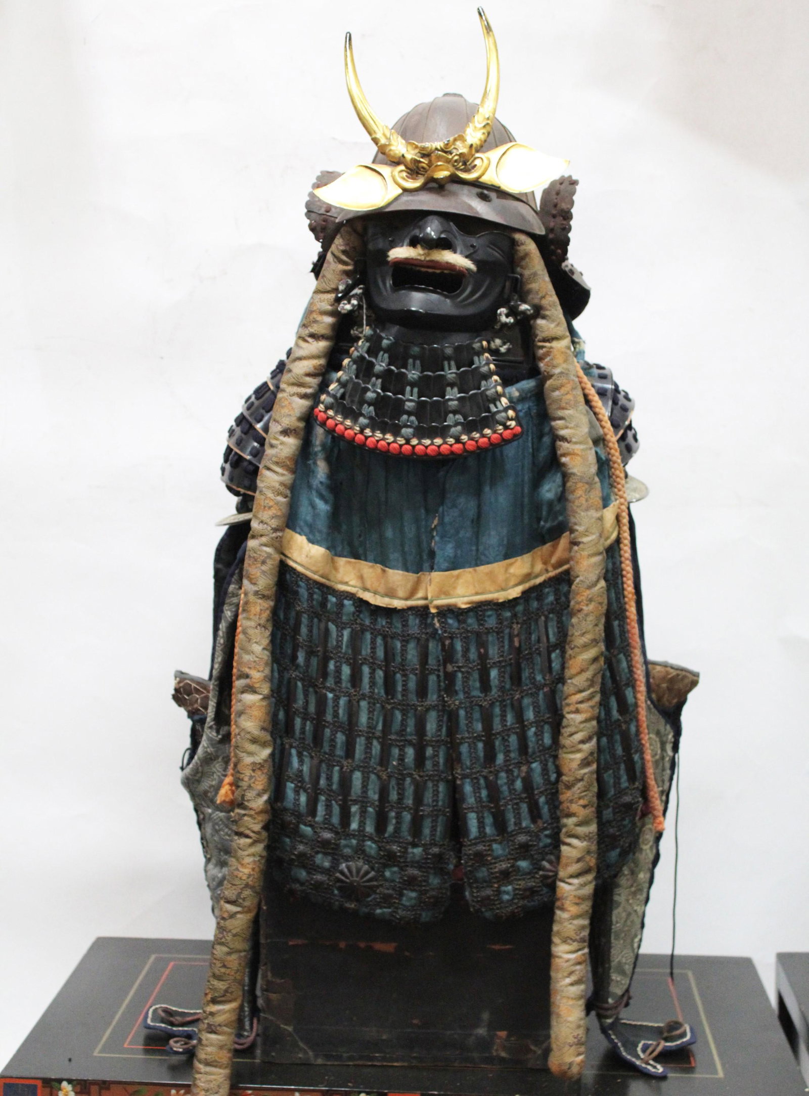 A JAPANESE SAMURAI GUSOKU ARMOR: The helmet with neck guard; half mask with throat guard; pair of shoulder guards; black lacquer cuirass with skirt; pair of sleeves with hand covers; thigh protectors; leg guards; and cloth pants and 