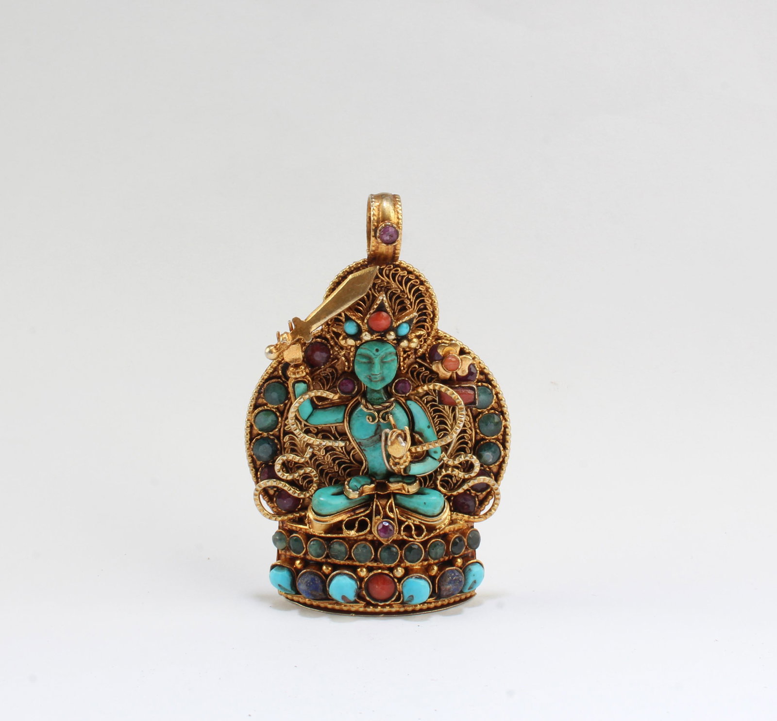 A Pendant with a figure of Majushiree, a God of Wisdom,: A Pendant with a figure of Majushiree, a God of Wisdom, with gold inlaid, turquois, and coral stones around and a good luck mantra, Nepal. Height: 2.75"Provenance: Private Collection of Yangki, Costa 