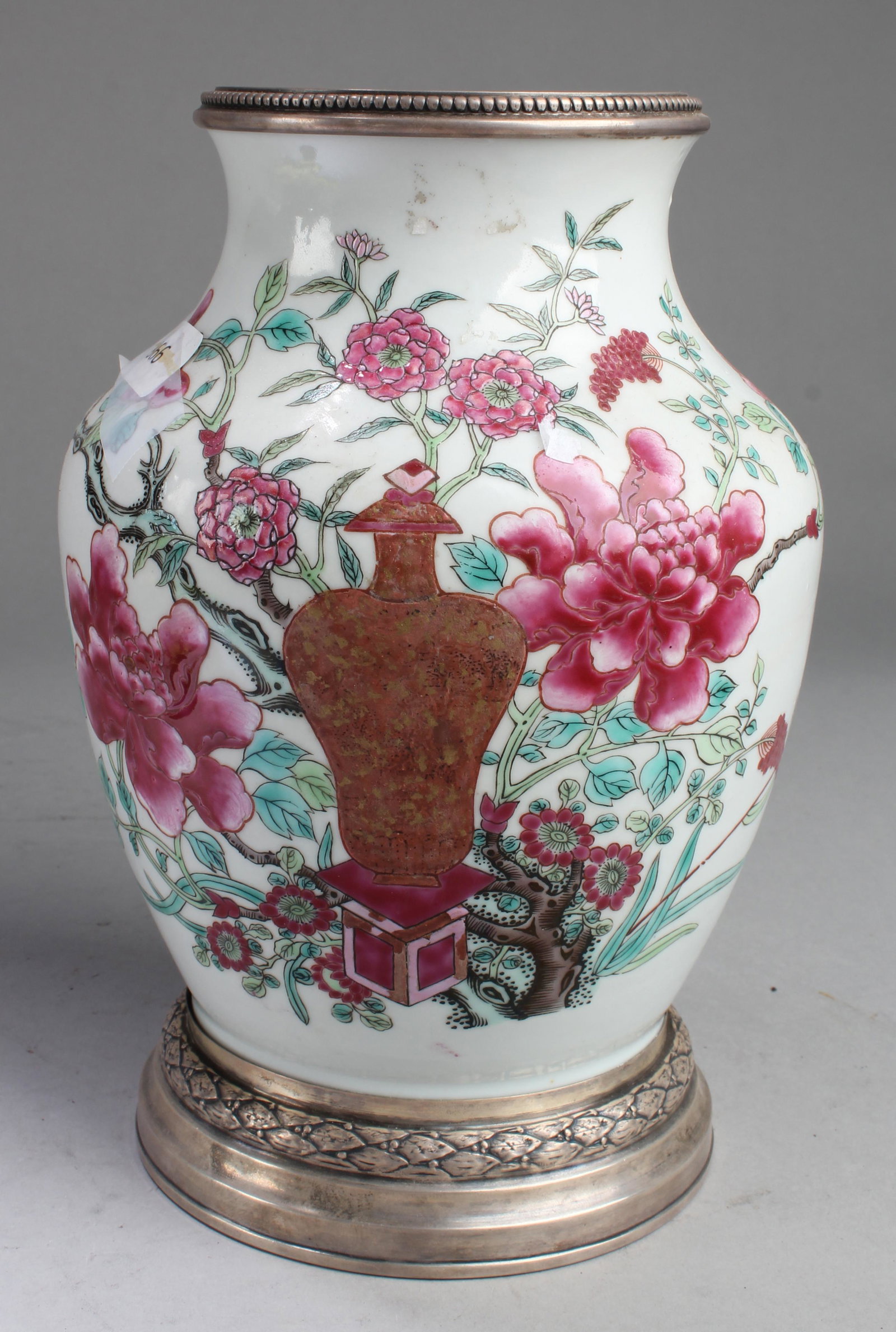 Chinese Antique Famille Rose Porcelain Vase: Of broad shoulders rising to a short flared neck, the porcelain vase is painted with a vase surrounded by flowers blossoms bourne from leafy stems. Diameter: 6 in Height: 9 in