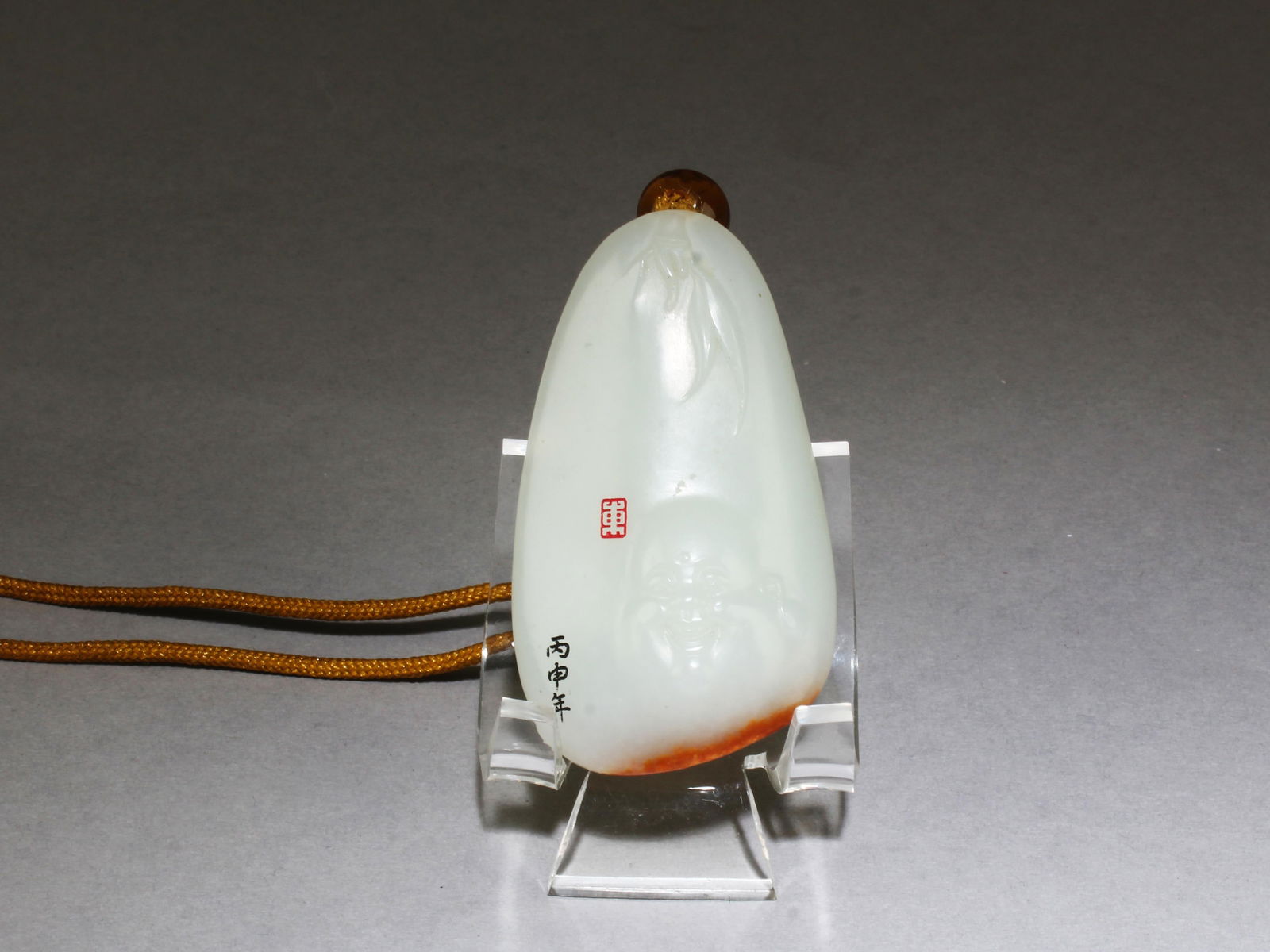 A Carved Jade Pendant: A Carved Jade Pendant, attached to a yellow string. Height: 2.3"