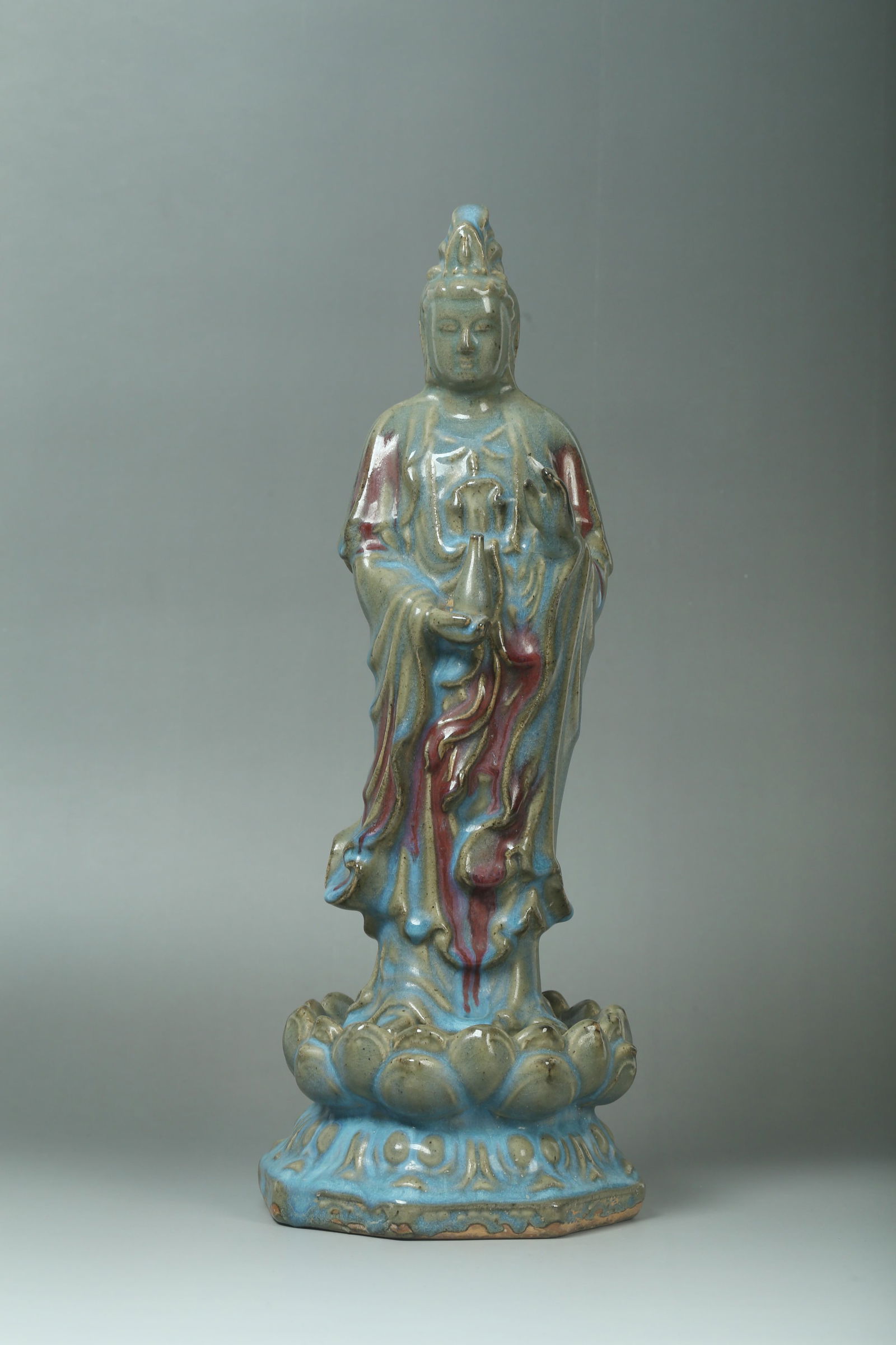 A Jun Type Standing Guanyin Statue: A Jun Type Standing Guanyin Statue, standing on a lotus throne, right hand holding a vase. Height: 16.5" Diameter: 6.5"
