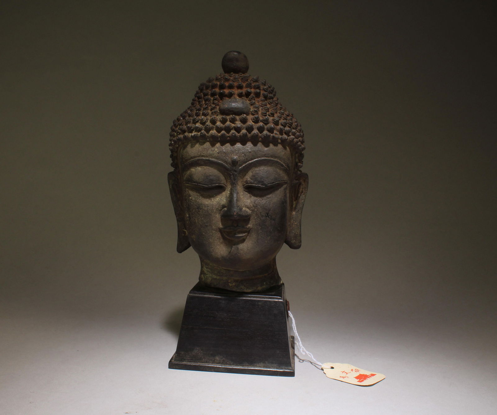 A Bronze Buddha Head: A Bronze Buddha Head with wooden stand. Dimension: 7.5 " x 5" Dimension inclusive of wooden stand: 10" x 7.5"