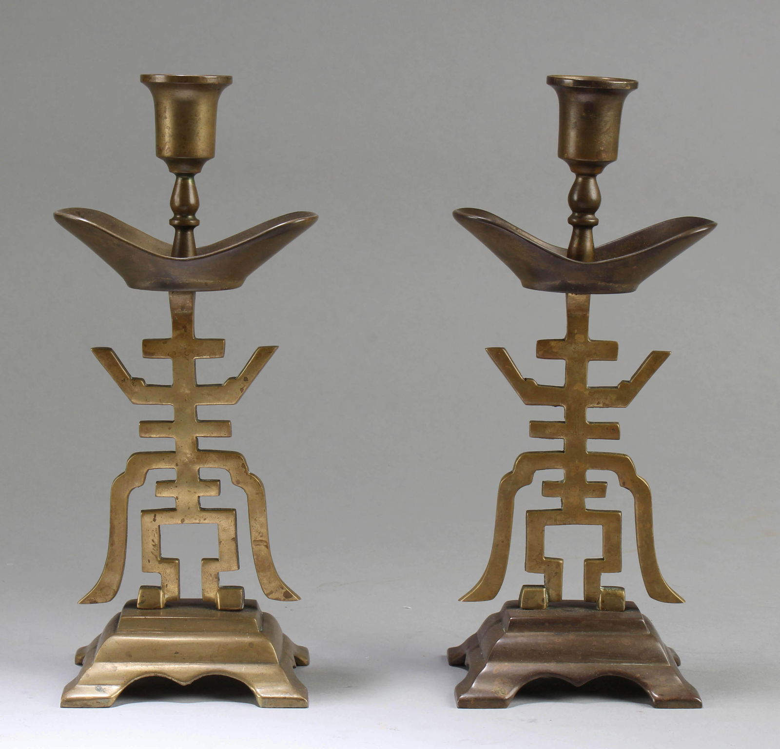 A Pair of Chinese Bronze Candle Holders: A Pair of Chinese Bronze Candle Holders, carved into the character 'Shou'. Height: 9"