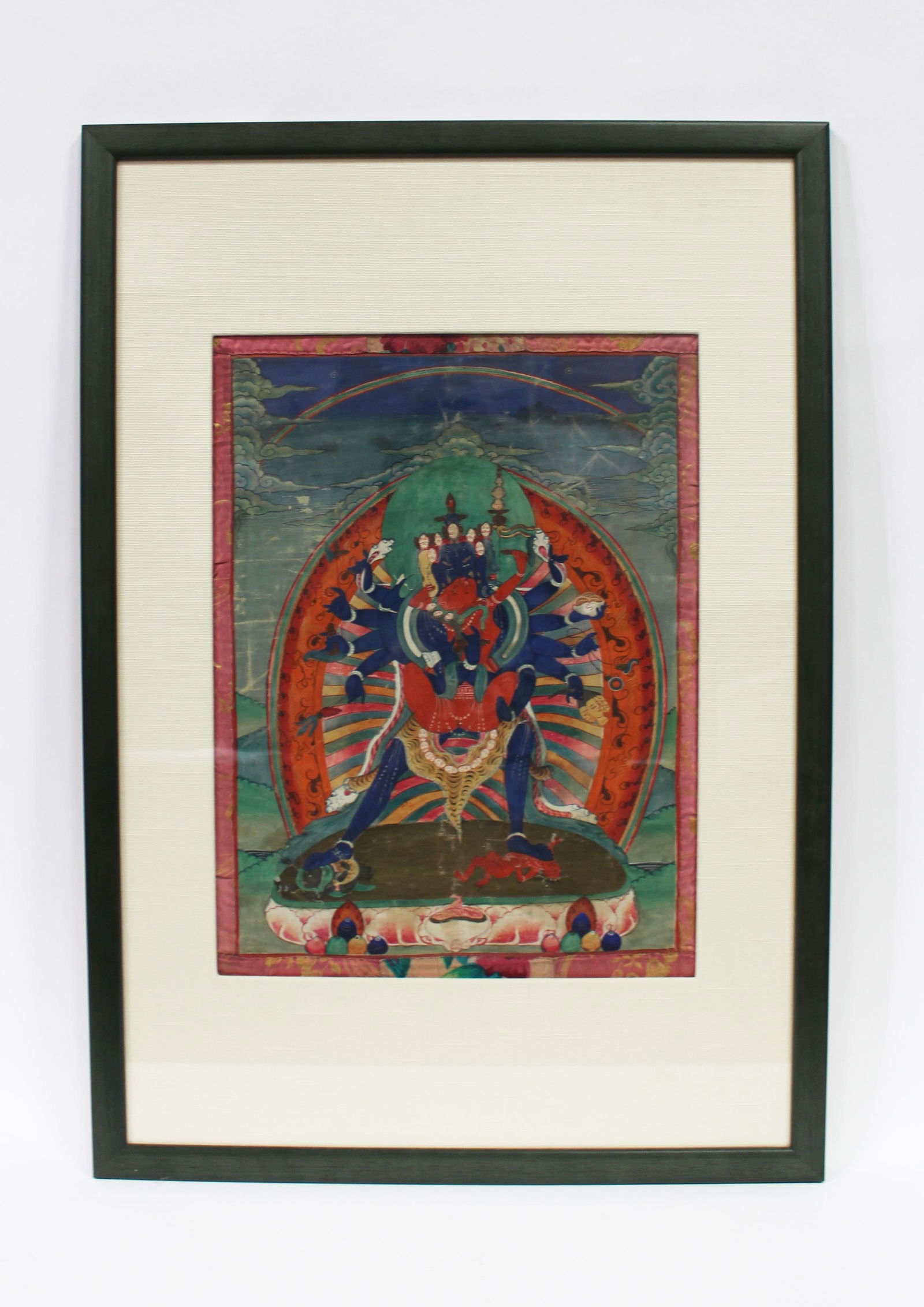 Antique Framed Painted Thangka: Antique painted thangka; of a wrathful deity and consort within a green hilly landscape; Provenance: Estate of Frederick L. Simmons; 16" x 12" (sight, approx.); matted and framed