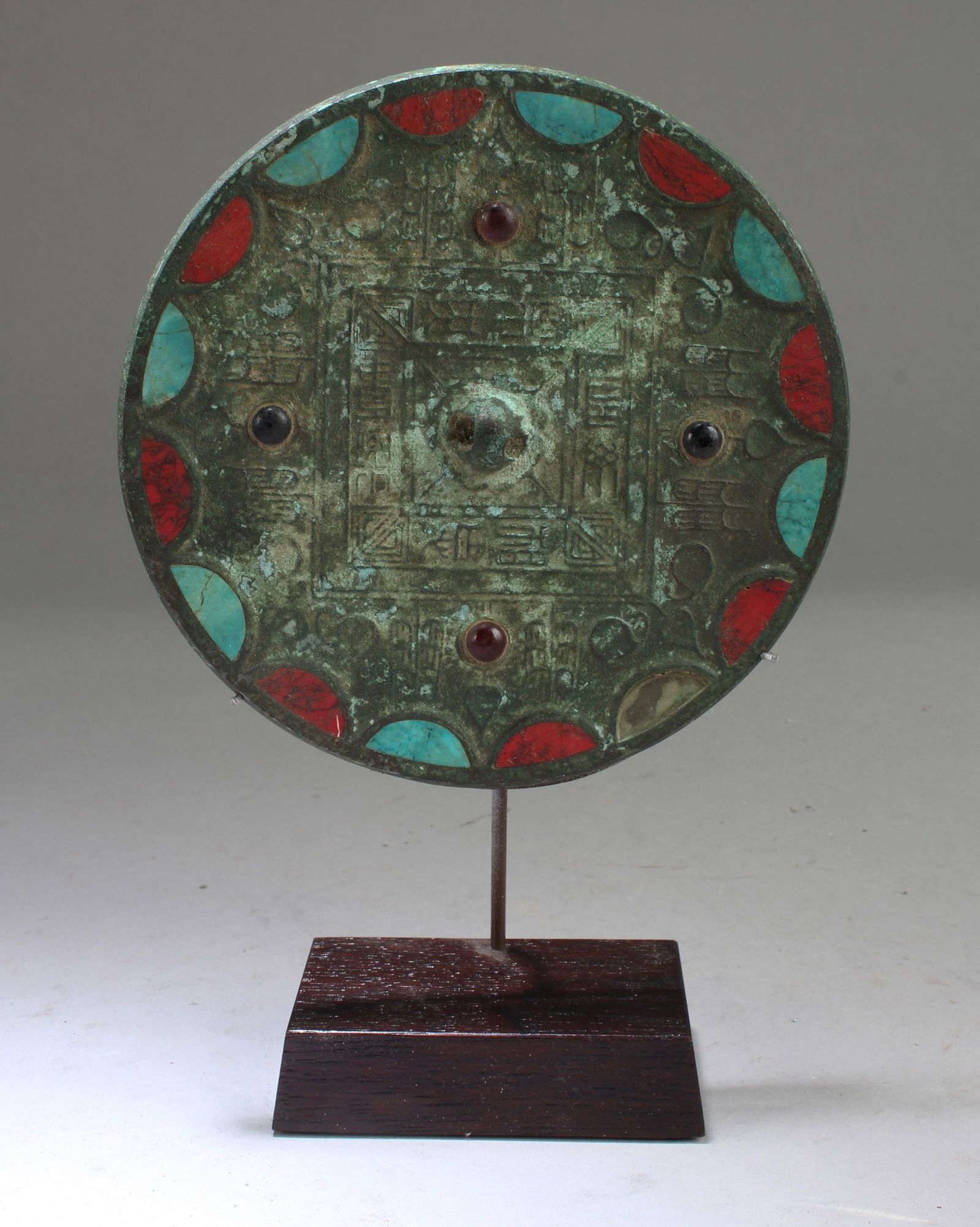 A Bronze Mirror with Red and Blue Turquoise Inlay: A Bronze Mirror with Red and Blue Turquoise Inlay. Comes fitted with a stand. Diameter: 5.25"