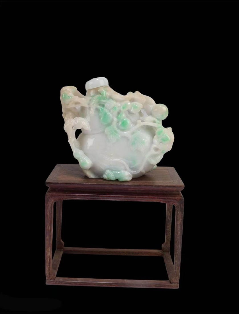 A Carved Jade Snuff Bottle: A Carved Jade Snuff Bottle. Comes fitted with a wooden stand. Height: 3.35"