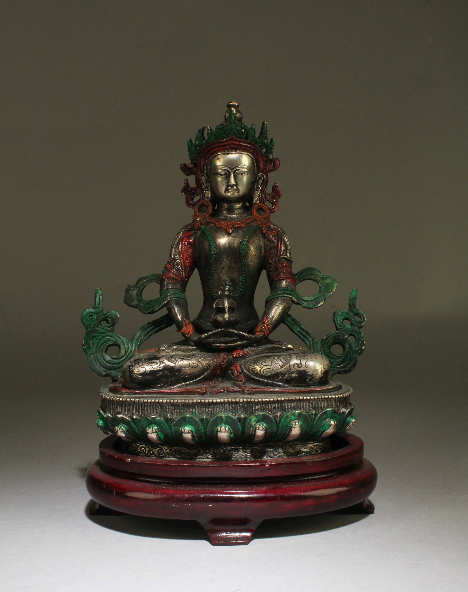 Chinese Bronze Bodhisattva Statue: Seated in dhyanasana on a lotus throne, both hands in front of the lap holding a religious item, chest adorned with beaded jewelry, wearing long flowing robe and headdress, the face with a serene expr
