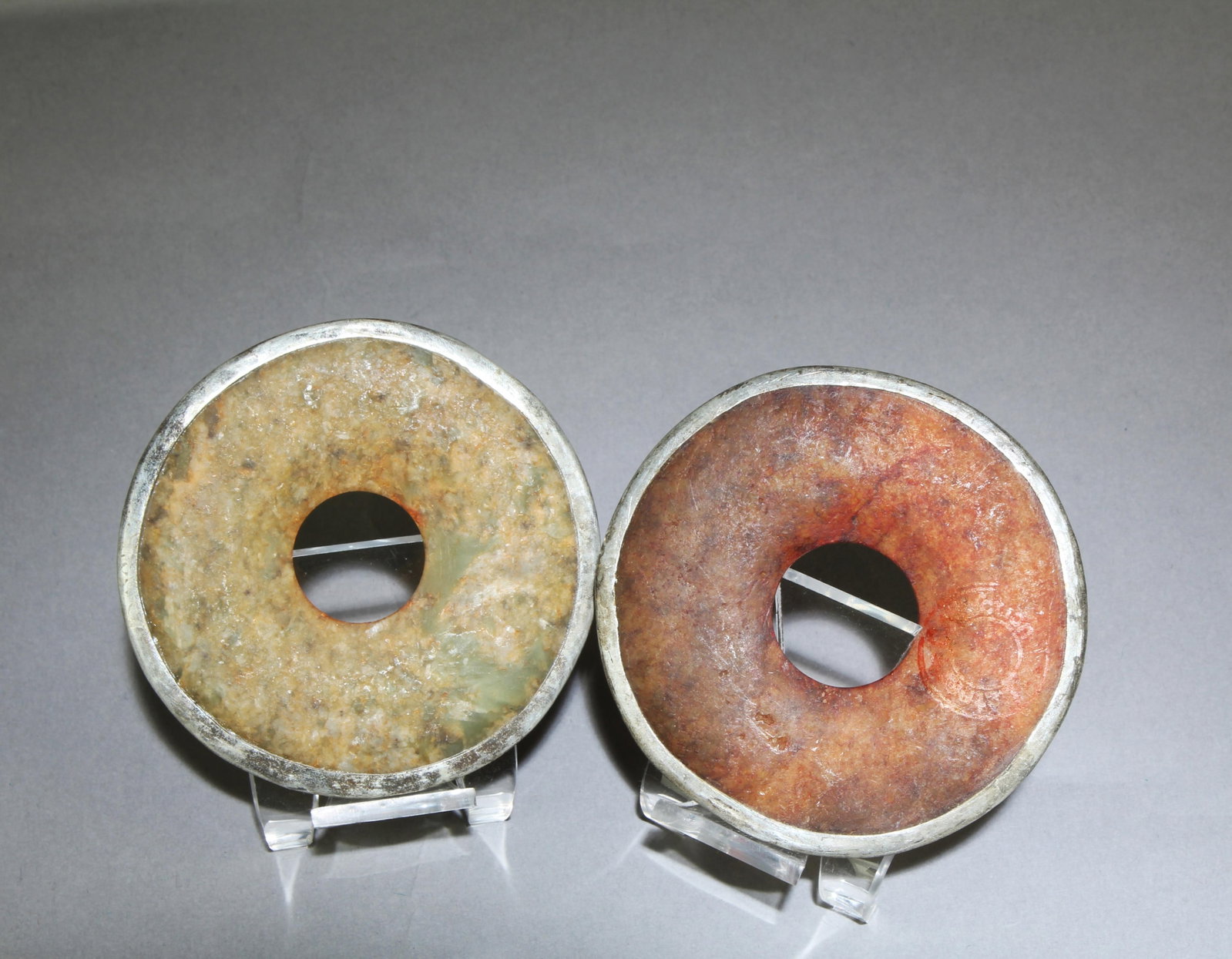 A Group of Two Jade Bi: A Group of Two Jade Bi, with silver encasing. Diameter: 3"
