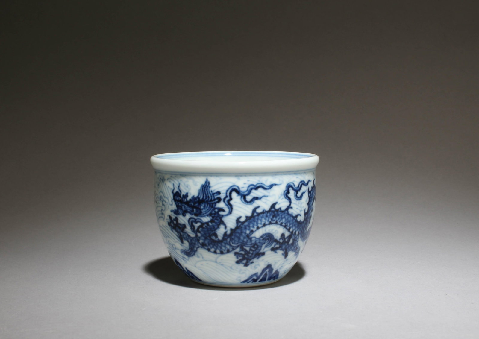 A Blue and White Cup with Dragon Motif: A Blue and White Cup with Dragon Motif. "XuanDe" mark at base. Dimensions: 3" x 2.2"