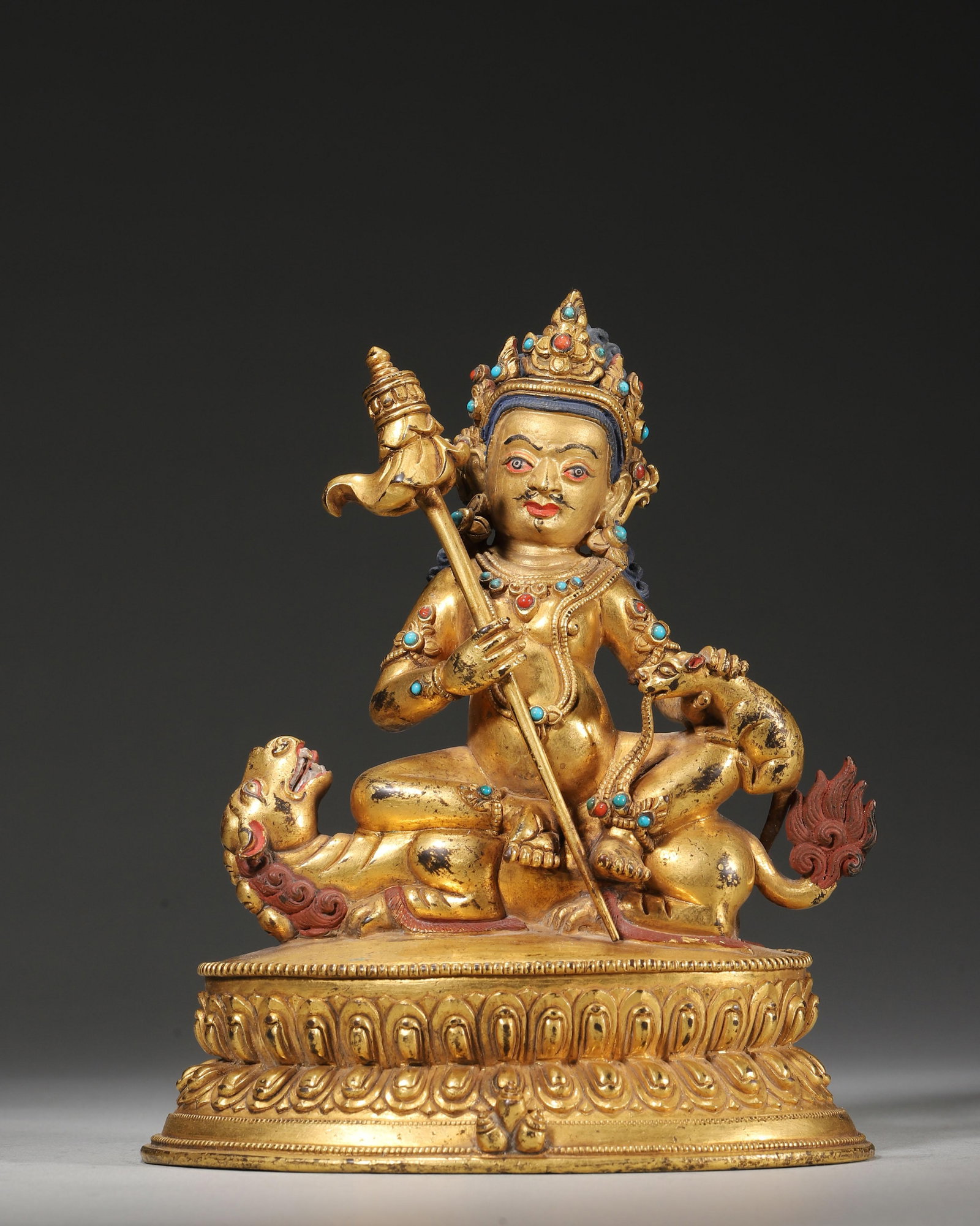 18TH-19TH CENTURY GILT-COPPER INLAID GEMSTONE STATUE OF JAMBHALA ON LION THRONE: 4.72" x 2.76" x 5.91" (12cm x 7cm x 15cm) | 1.85lb (837g)This 18th-19th century Tibetan Buddhist statue depicts Jambhala, cast in gilt copper with turquoise and coral inlay, seated on a lion throne. H