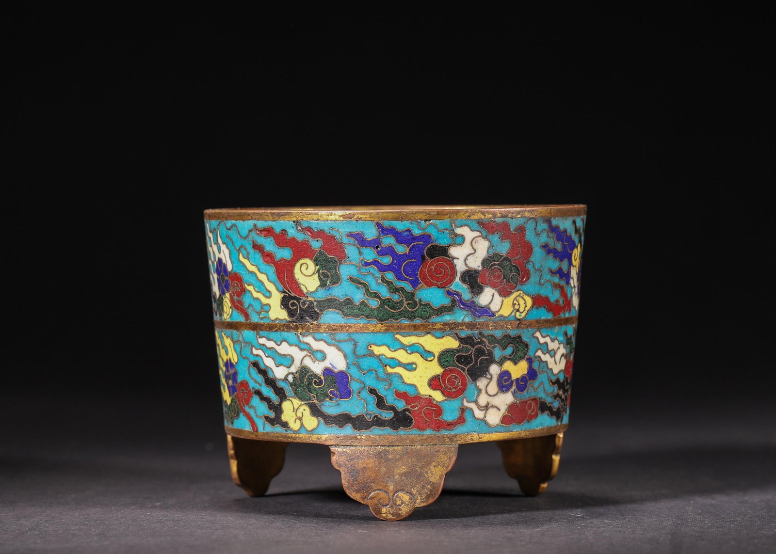 A GILT-BRONZE CLOISONNE ENAMEL TRIPOD CENSER WITH CLOUD PATTERN, MING DYNASTY: Diameter 9.5cm (3.74in), Height 7.2cm (2.83in), Weight 318.0g (0.7lb)A gilt-bronze tripod censer from the Ming Dynasty, cast in a straight cylindrical form with three ruyi-shaped feet. The body featur