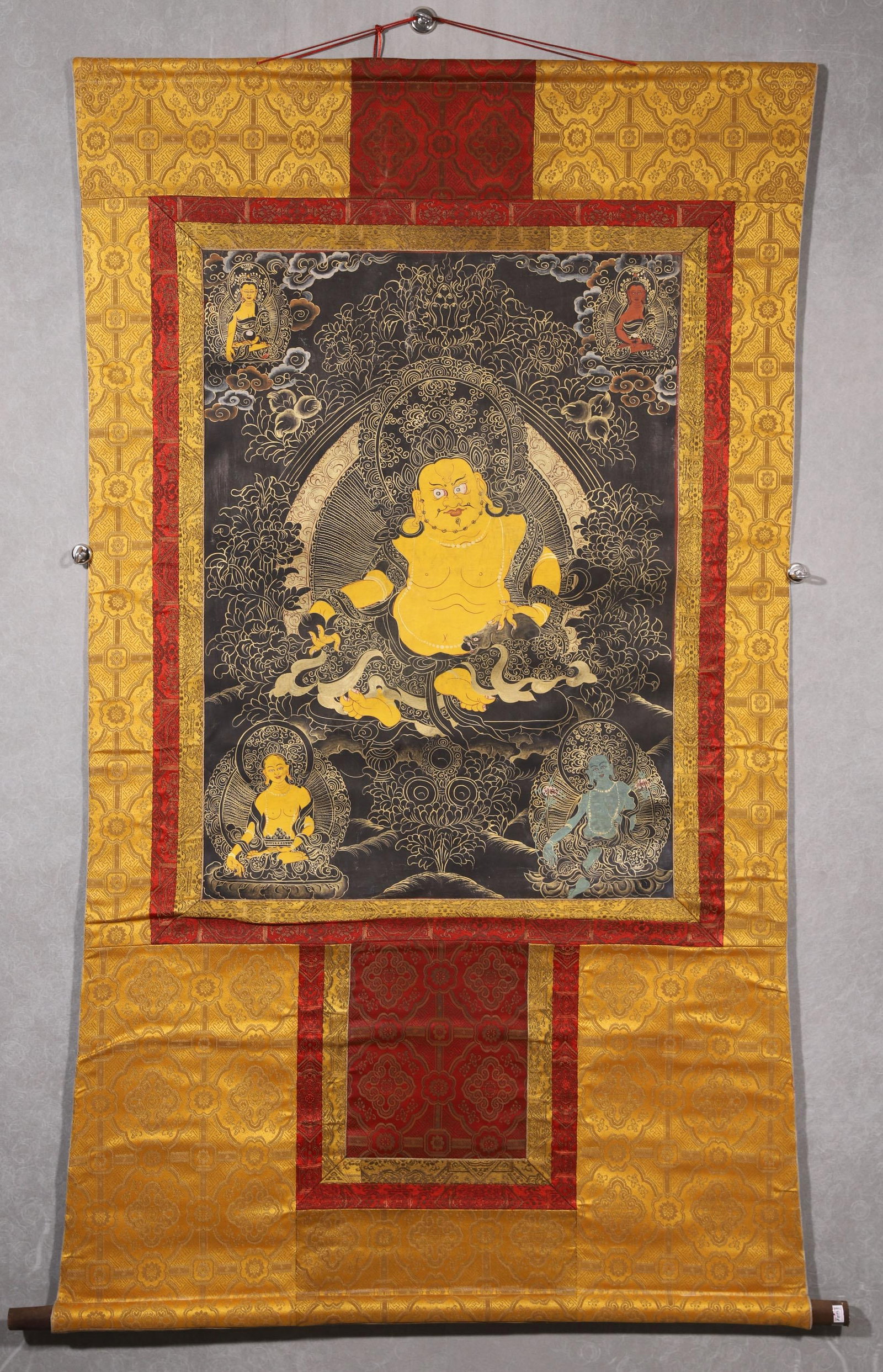 A YELLOW JAMBHALA BLACK-BACKGROUND THANGKA - QING DYNASTY: Length 78.0cm (30.71in), Width 58.0cm (22.83in)This Qing Dynasty thangka depicts Yellow Jambhala in black-background style, painted with mineral pigments and gold on cotton. The wealth deity sits sere