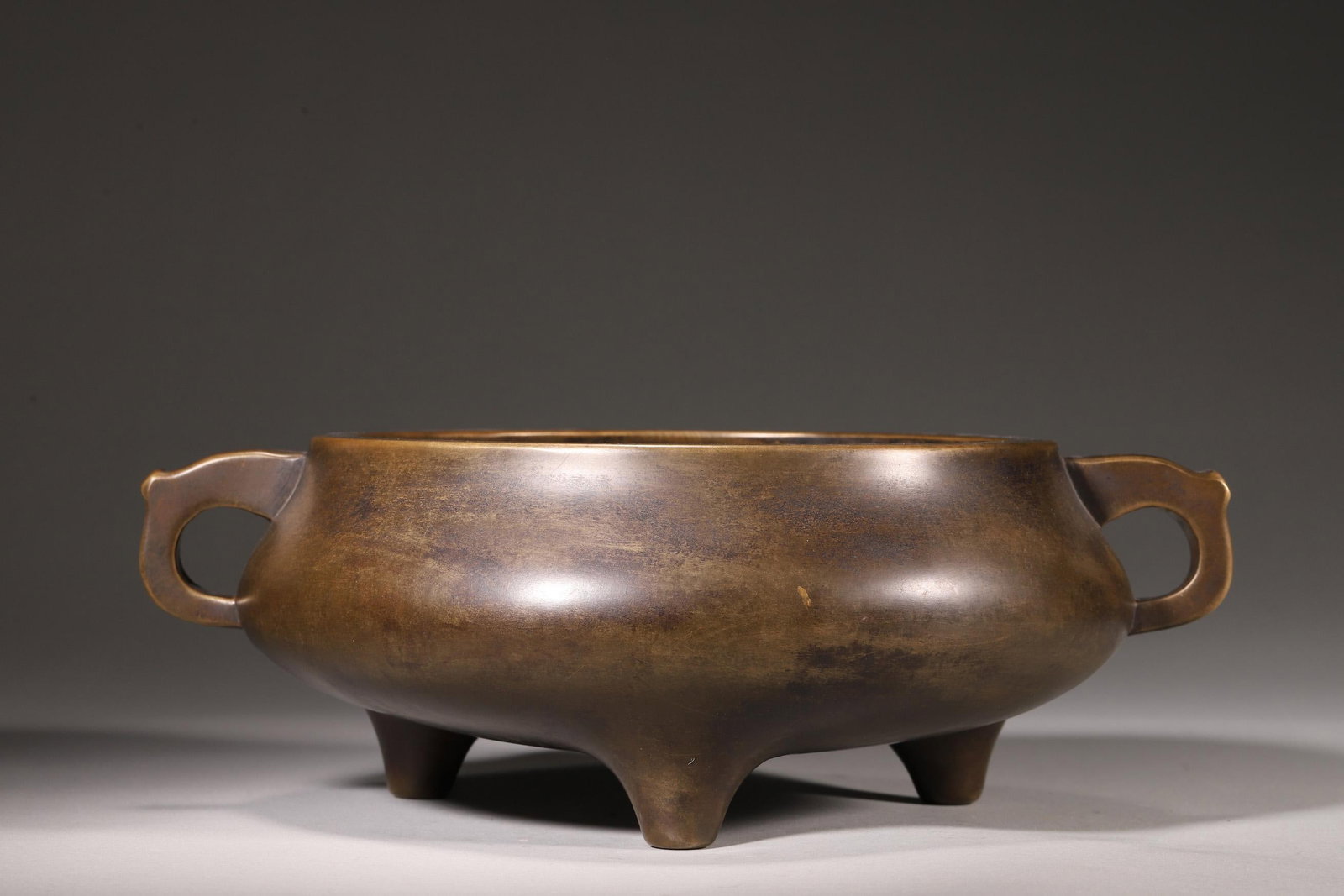 A BRONZE THREE-FOOT CENSER WITH PAN HANDLES, "XUANDE NIAN ZHI" MARK, MING DYNASTY: Width 26.0cm (10.24in), Height 9.0cm (3.54in), Weight 3142.0g (6.93lb)A bronze three-foot censer with pan handles, bearing the "Xuande Nian Zhi" mark, dating to the Ming Dynasty. Cast from refined bro