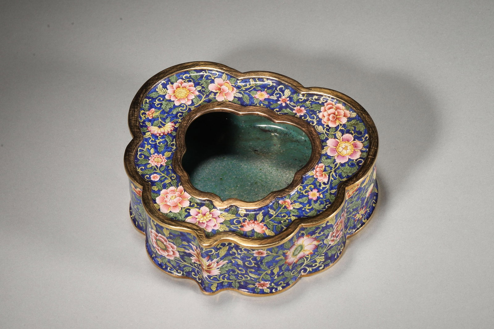 AN ENAMELED COPPER WATER POT WITH FLORAL SCROLLS, QIANLONG PERIOD: 11.5cm x 10.0cm x 4.0cm,445.0g (4.53in x 3.94in x 1.57in,WT 0.9811lb)This enameled copper water pot features floral scrolls on a blue ground, with gilt rims and a Qianlong mark. It exemplifies the opu