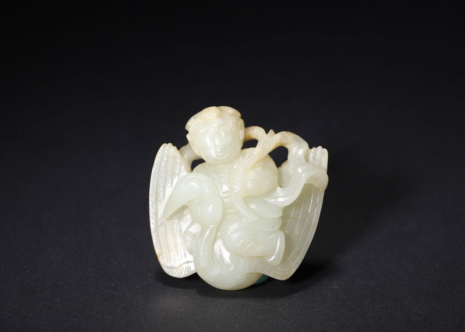 QING DYNASTY PALE GREEN JADE CARVED BOY ON CRANE PENDANT: 1.89in x 1.97in (4.8cm x 5.0cm) | 0.110lbs (50g)A fine Qing Dynasty pale green jade pendant, carved with a serene boy seated on a crane, holding a sprig. The smooth texture, delicate details, and warm