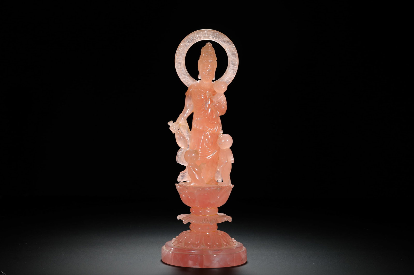 A QING DYNASTY ROSE CRYSTAL STATUE OF GUANYIN GIVING BIRTH: H:26cm (10.24in) W:10cm (3.94in) Weight:990g (2.18lb)Solid rose quartz carved standing guanyin holding kids on double lotus pedestal.