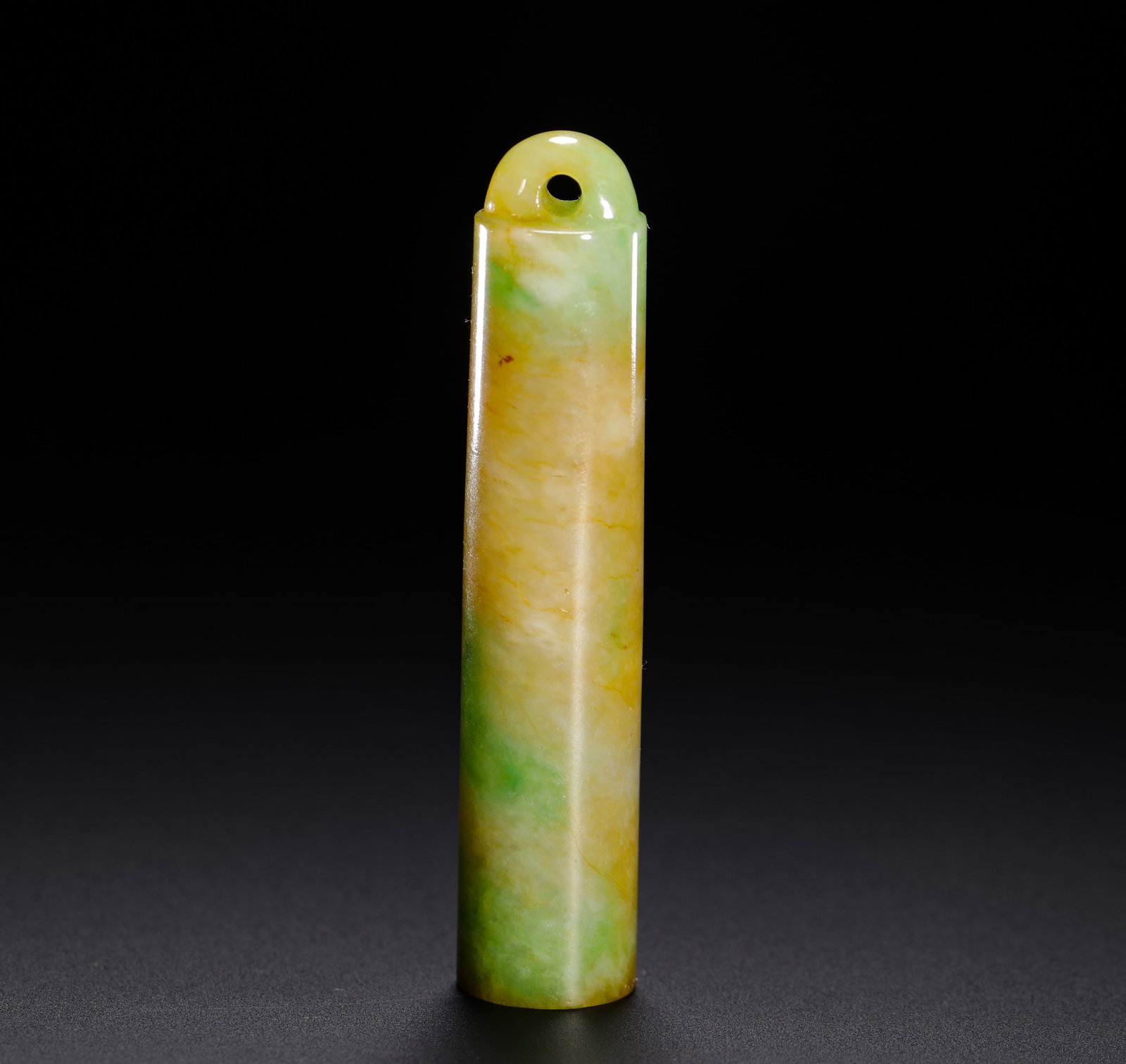 QING DYNASTY YELLOW JADEITE GREEN FEATHER TUBE: H:6cm (2.36in) D:1.2cm (0.47in) Weight:15g (0.03lb)Qing official feather tube, entirely carved from yellow-jadeite with scattered emerald green, top with suspension hole for mandarin hat ornament.