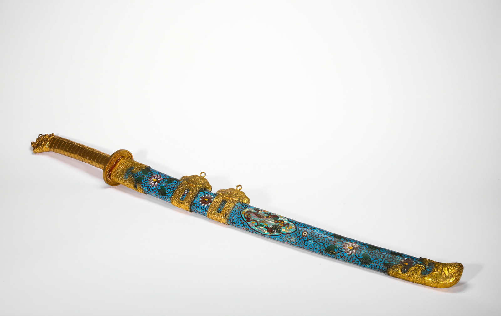 BRONZE GILT CLOISONNE ENAMEL DRAGON PATTERN IMPERIAL KNIFE OF THE QING DYNASTY: L:105cm (41.34in) Weight:3120g (6.88lb)Ceremonial saber with gilt beast hilt and cloisonne scabbard decorated with phoenix & dragon amid scrolling flora.