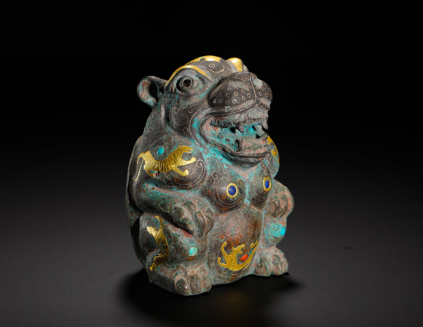 THE HAN DYNASTY INLAID GOLD AND SILVER INLAID TREASURE CROUCHING BEAR SEAT TOWN: H:9cm (3.54in) W:7cm (2.76in) Weight:470g (1.04lb)Crouched bear bronze mat weight, silver scroll ground, gold inlaid small beasts, inset turquoise & coloured gems.
