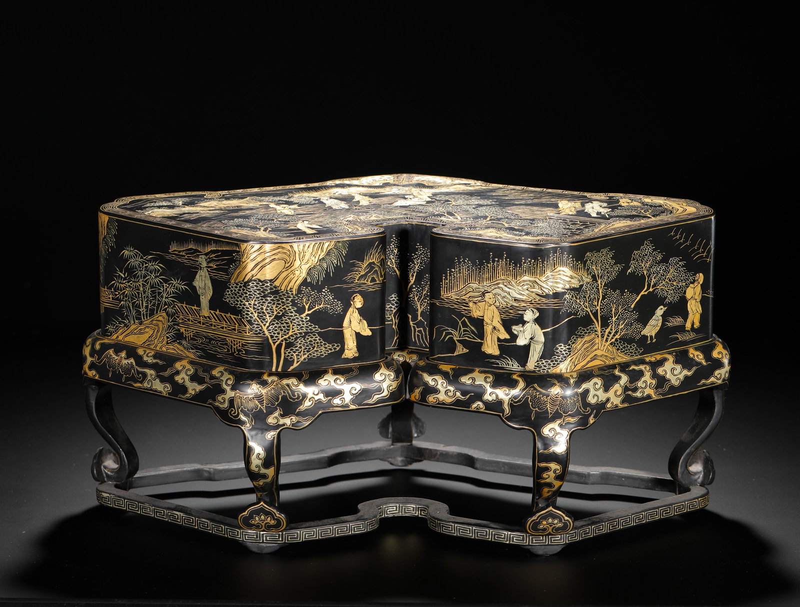 QING DYNASTY BLACK LACQUER GILDED LANDSCAPE AND FIGURE DOUBLE COUPLET TREASURE BOX: H:20cm (7.87in) W:35cm (13.78in)Double-lobed lacquer casket finely painted with gold scenic figures, matching gilt cloud-carved wooden stand.