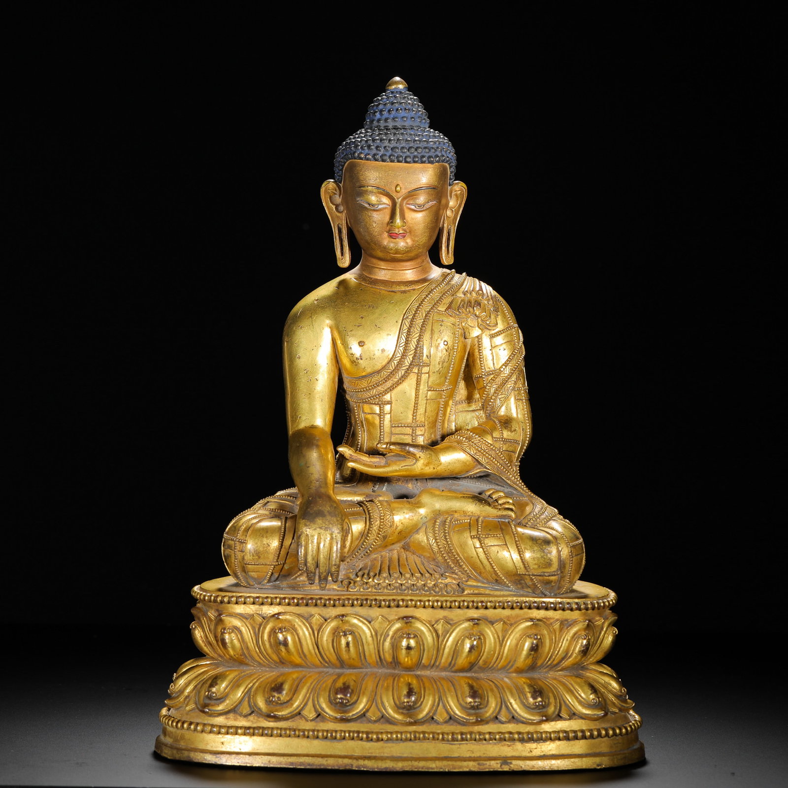 A GILDED BRONZE STATUE OF THE ENLIGHTENMENT OF SAKYAMUNI BUDDHA FROM THE QING DYNASTY: H:34cm (13.39in) W:35cm (13.78in) Weight:6270g (13.82lb)This is a Qing Dynasty gilt bronze seated statue of Shakyamuni Buddha in the Tibetan Buddhist style, featuring exquisite craftsmanship and under
