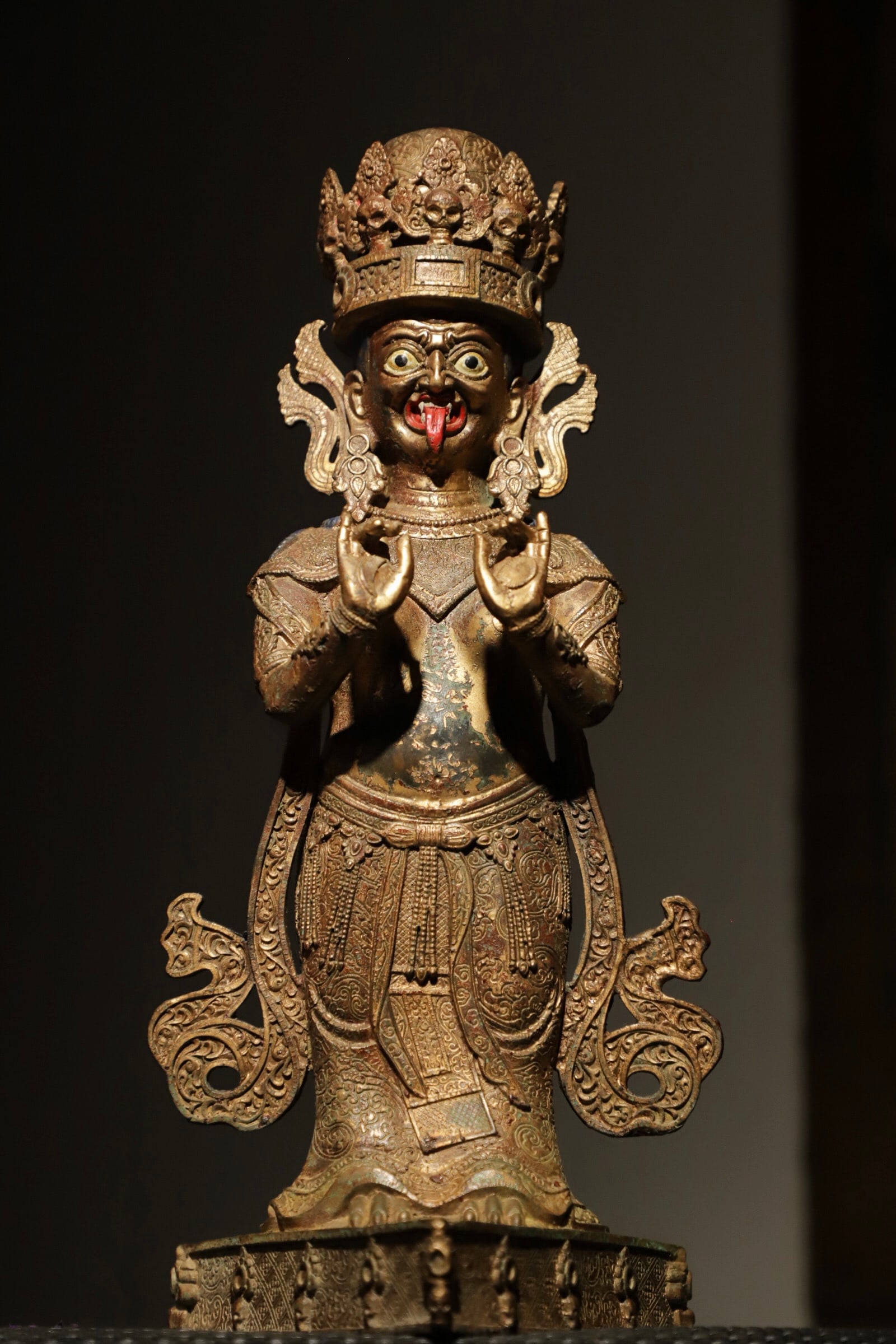 A STANDING STATUE OF TIBETAN DHARMA PROTECTORS IN GILDED COPPER FROM THE MING DYNASTY: Weight:2000g=2.00kg(4.41lb);H:32cm(12.60in) L:15cm(5.91in) W:12cm(4.72in)A gilded bronze standing Tibetan Dharma protector statue, wearing a skull jewel crown with a wrathful face and red tongue, full