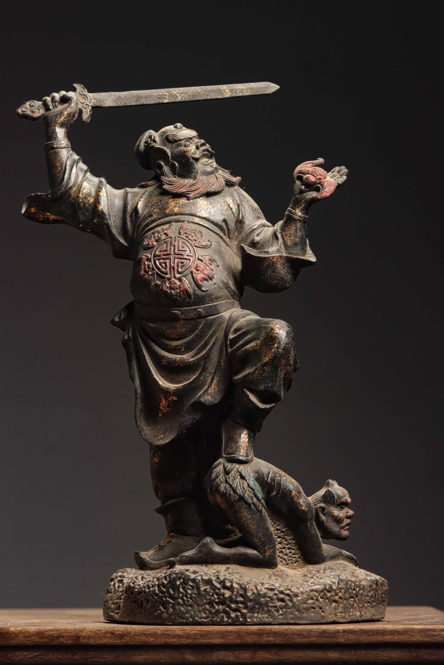 A GILDED BRONZE STATUE OF ZHONG KUI FROM THE QING DYNASTY: Weight:7300g(16.10lb)H:41cm(16.14in)W:27cm(10.63in)T:15cm(5.91in)This Zhong Kui sculpture features vigorous majestic posture with wrathful visage. One hand holds a sword aloft, the other holds an ausp