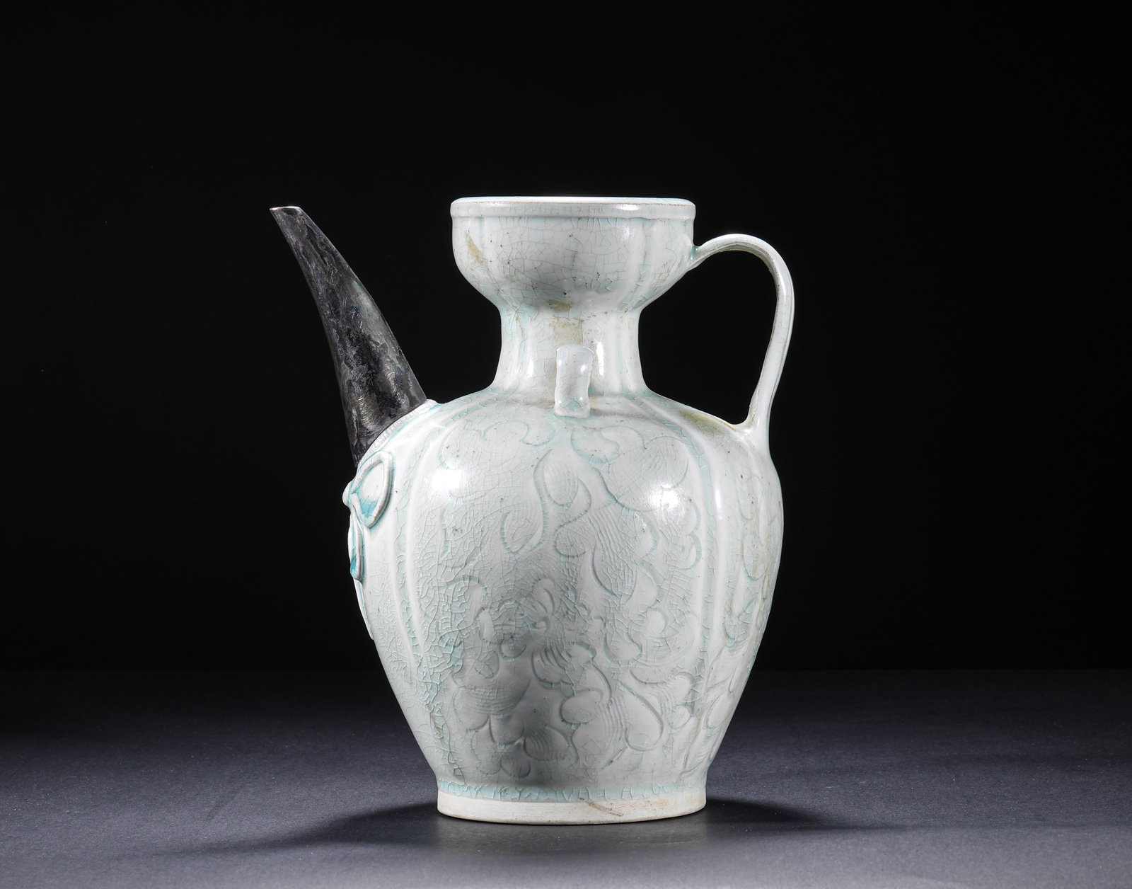 SONG DYNASTY SHADOW BLUE GLAZED ENGRAVED FLOWER EWER: H:20.0cm(7.87in) W:18.0cm(7.09in)This ewer is a classic form of the Song Dynasty Hutian Kiln, featuring a dish mouth, slender neck, melon-shaped ribbed body, curved handle, and a long silver spout inl