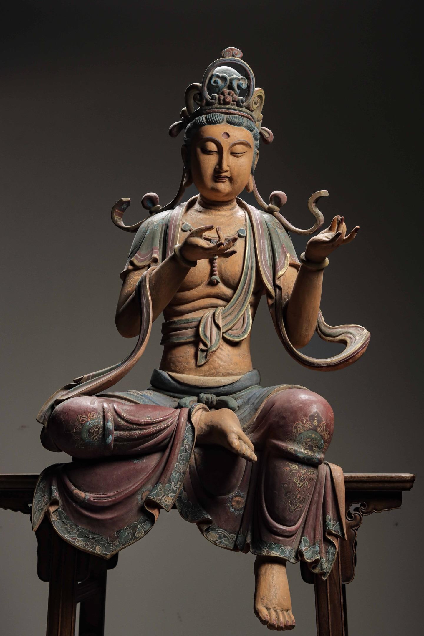 A SITTING STATUE OF THE FREE-SPIRITED GUANYIN IN WOOD CARVING AND PAINTED LACQUER FROM THE SONG: H:118cm(46.46in)W:65cm(25.59in)T:42cm(16.54in)This sculpture depicts Avalokitesvara in a relaxed half-lotus sitting posture, wearing an exquisite crown with gentle serene merciful facial features and 