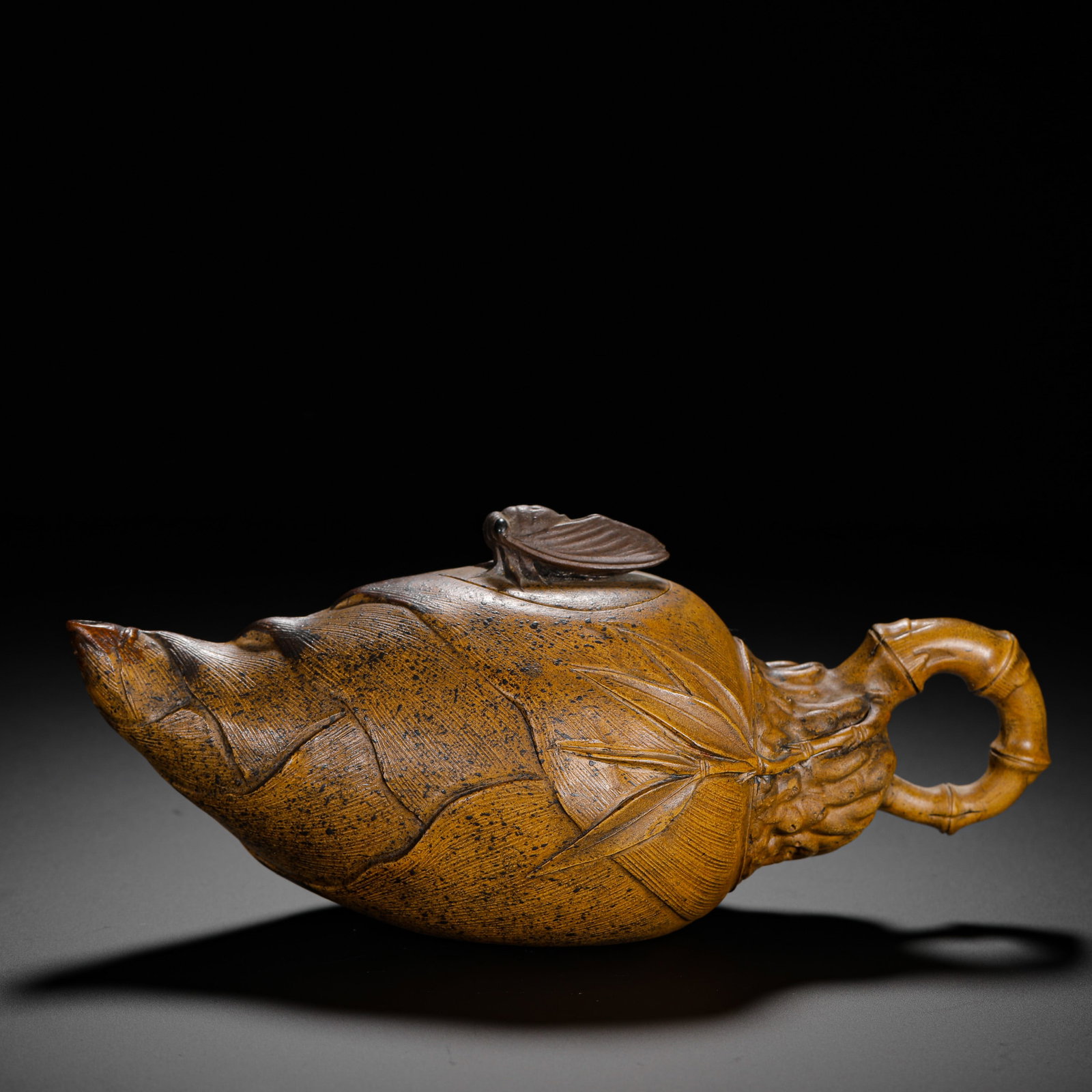 QING DYNASTY CHEN MINGYUAN PURPLE CLAY BAMBOO SHOOT TEAPOT: H:9.5cmW:21.5cmWeight:350g Biomorphic floral Zisha teapot crafted from Duan clay, shaped as fresh spring bamboo shoot with finely carved husk veins and bamboo leaves. Bamboo-joint handle, lid knob car