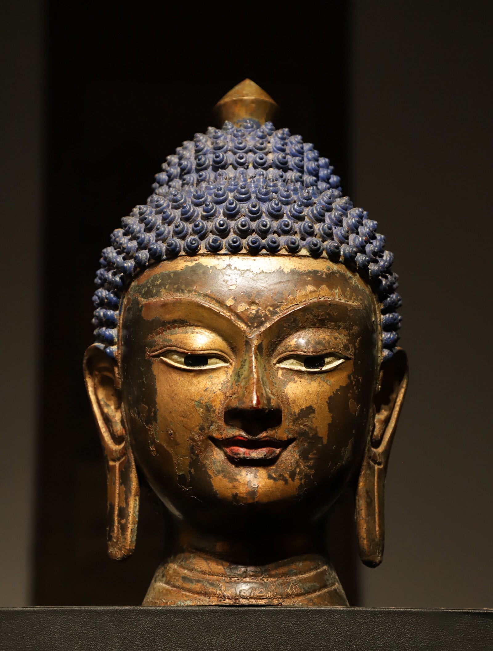 BRONZE GILDED BUDDHA HEAD OF THE MING DYNASTY: Weight:2350g (5.18lb) H:27cm (10.63in) L:17cm (6.69in) W:17cm (6.69in)This is a fragmented head sculpture of Sakyamuni Buddha in Tibetan style. It features a tall sharp ushnisha on top, with full neat